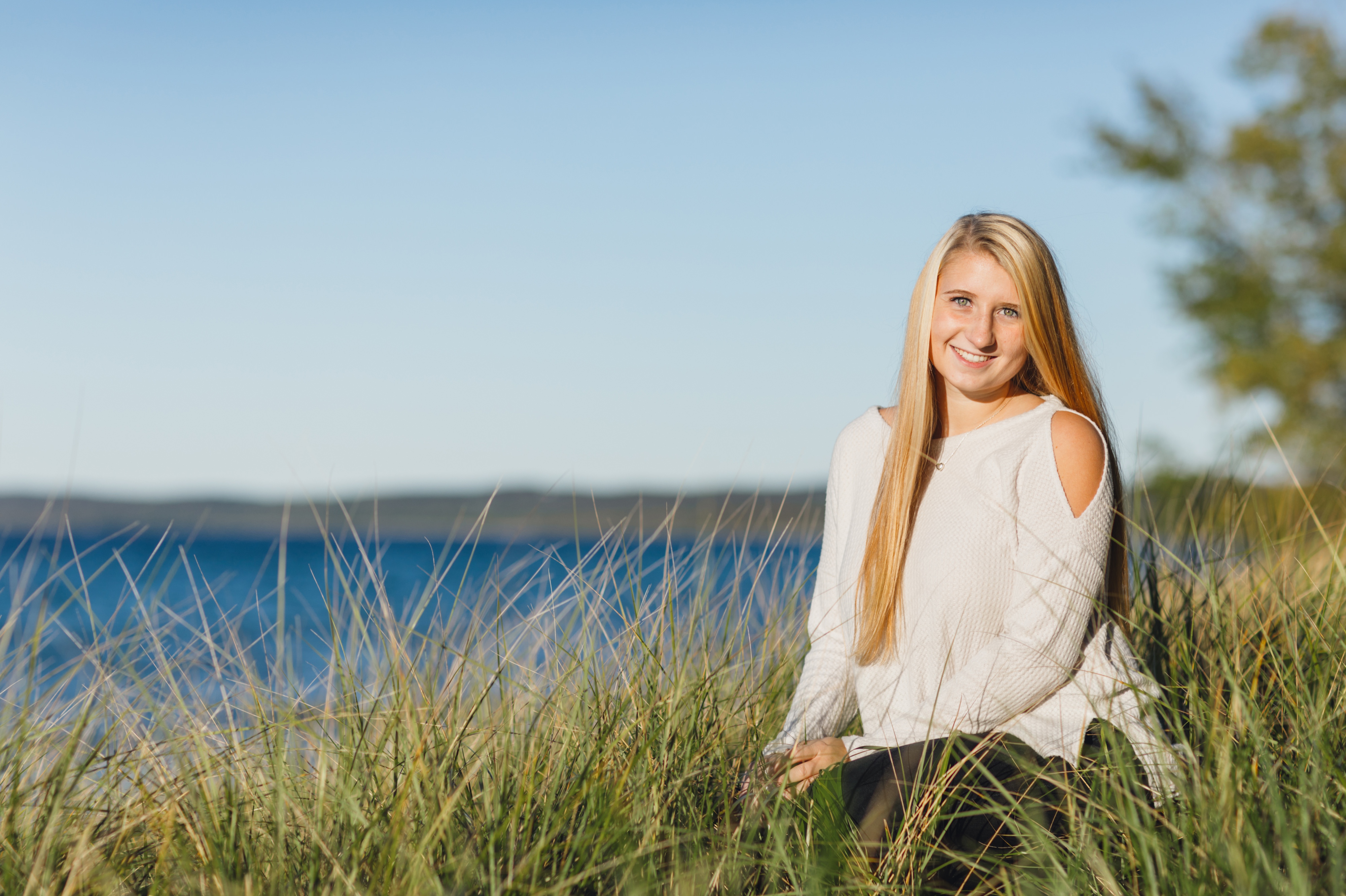 high school girl sitting on the beach in Leland Michigan