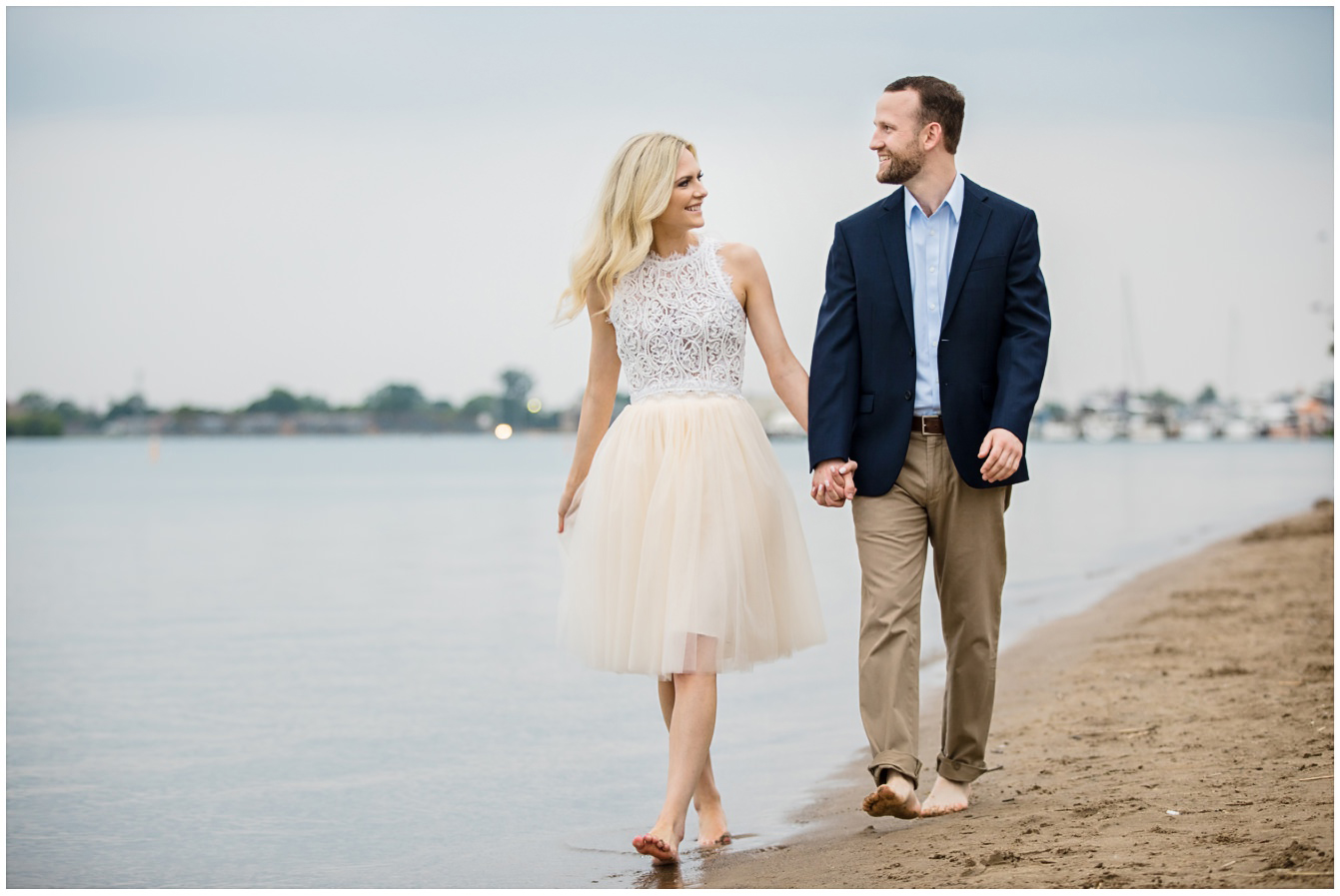 Man and woman walking during an engagement session on the beach at Belle Isle