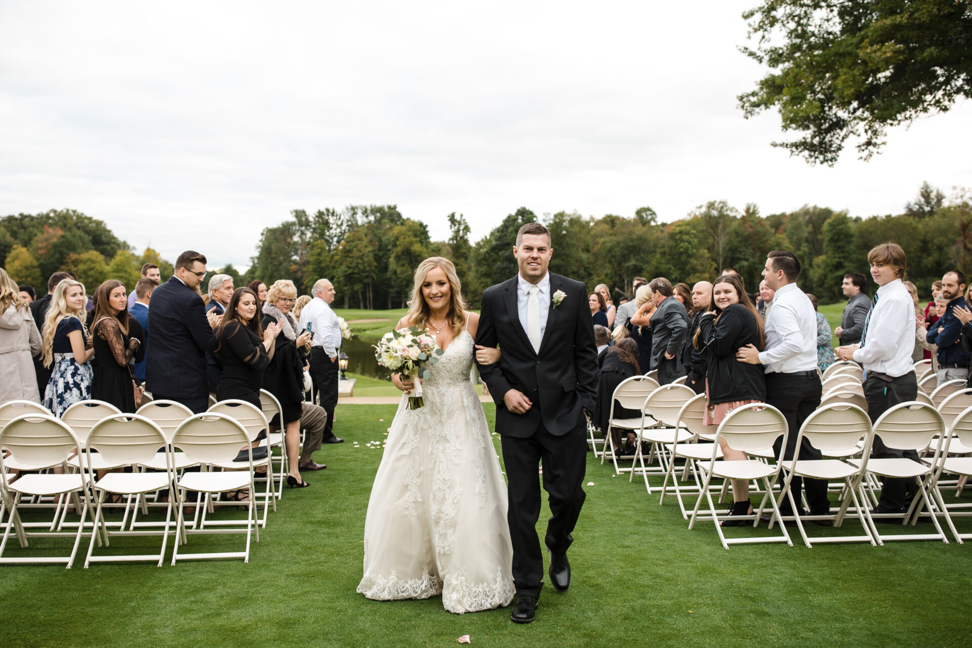 bride and groom just married overlooking the water at Cherry Creek Golf Club surrounded by friends and family
