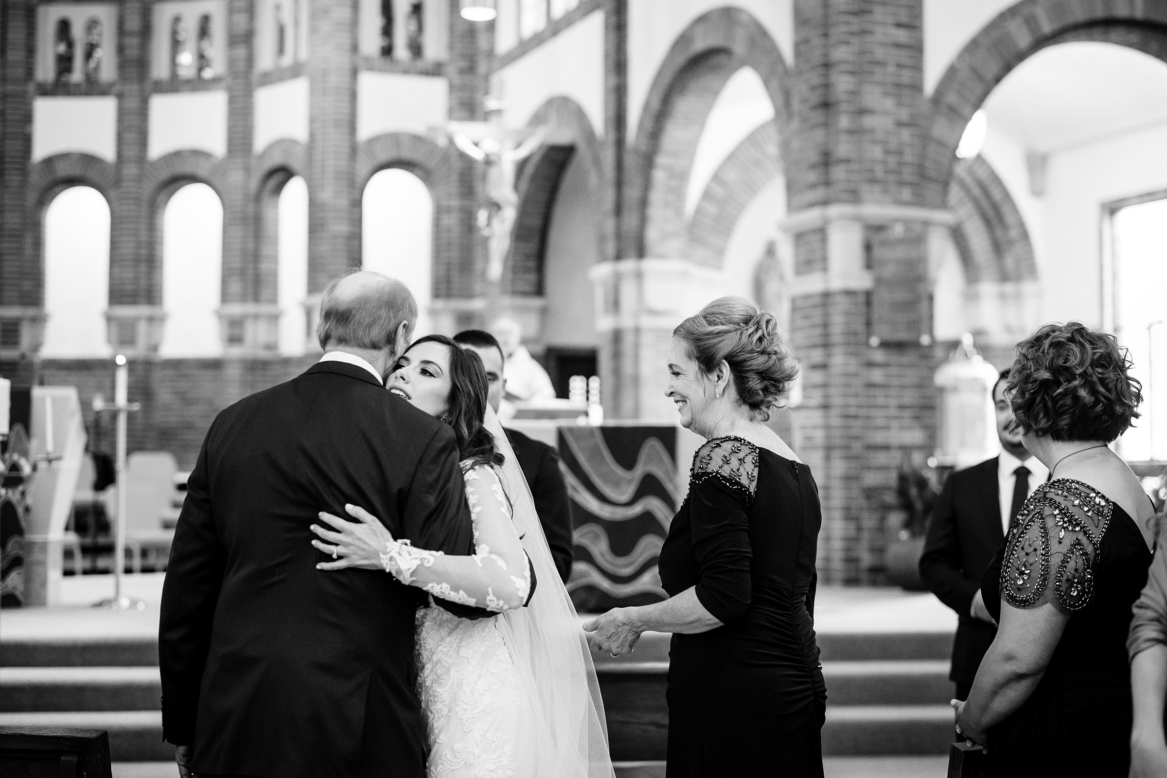 Black and white photo of the bride hugging her dad at the end of their aisle by Detroit Wedding Photographer Michele Maloney