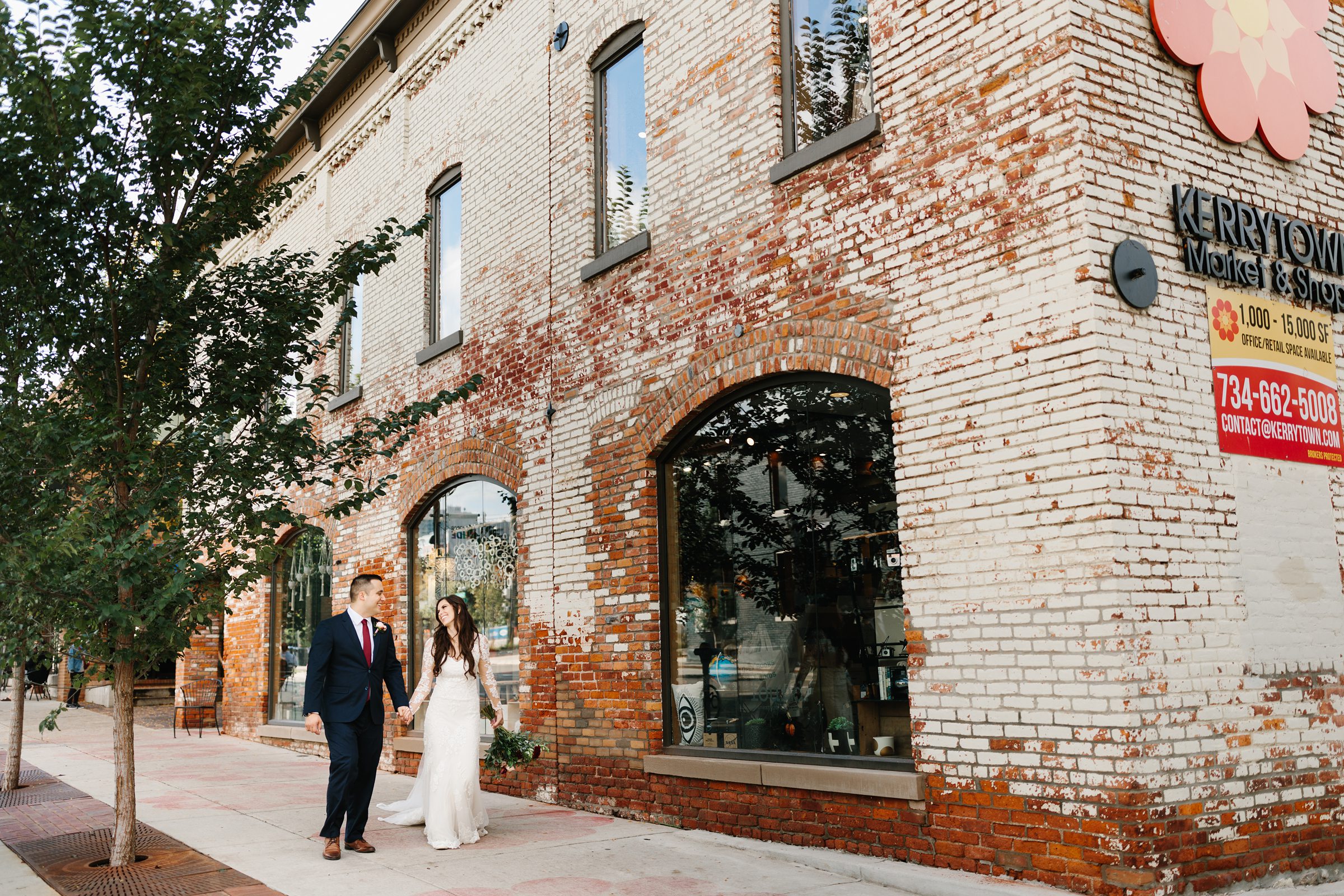 Bride and groom hold hands outside and stroll together in an urban setting for the Ann Arbor intimate wedding by Detroit Wedding Photographer Michele Maloney