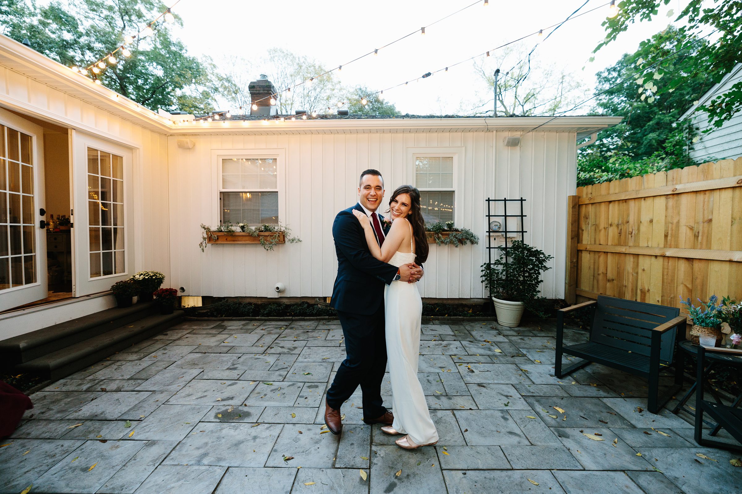 Bride and groom hold each other close in their backyard during the Ann Arbor intimate wedding reception, bride and groom are smiling and happy by Detroit Wedding Photographer Michele Maloney