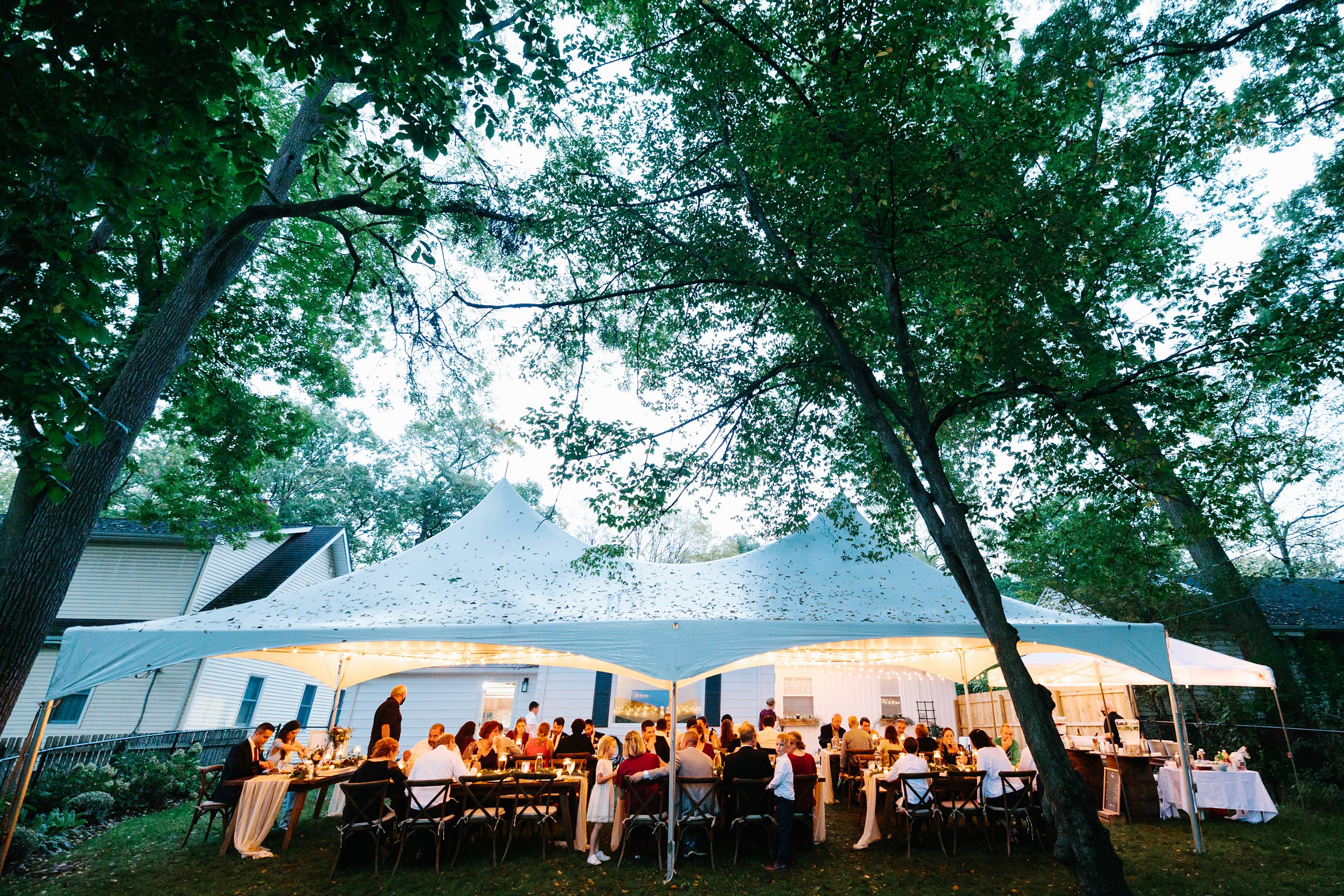 Faraway evening shot of the Ann Arbor intimate wedding under the canopy outside by Detroit Wedding Photographer Michele Maloney