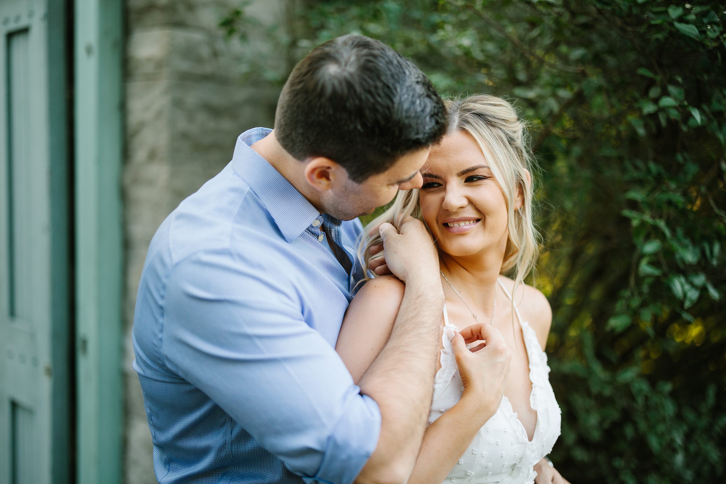 Future bride and groom snuggle close, bride to be looks back at her significant other and smiles by Detroit Wedding Photographer Michele Maloney