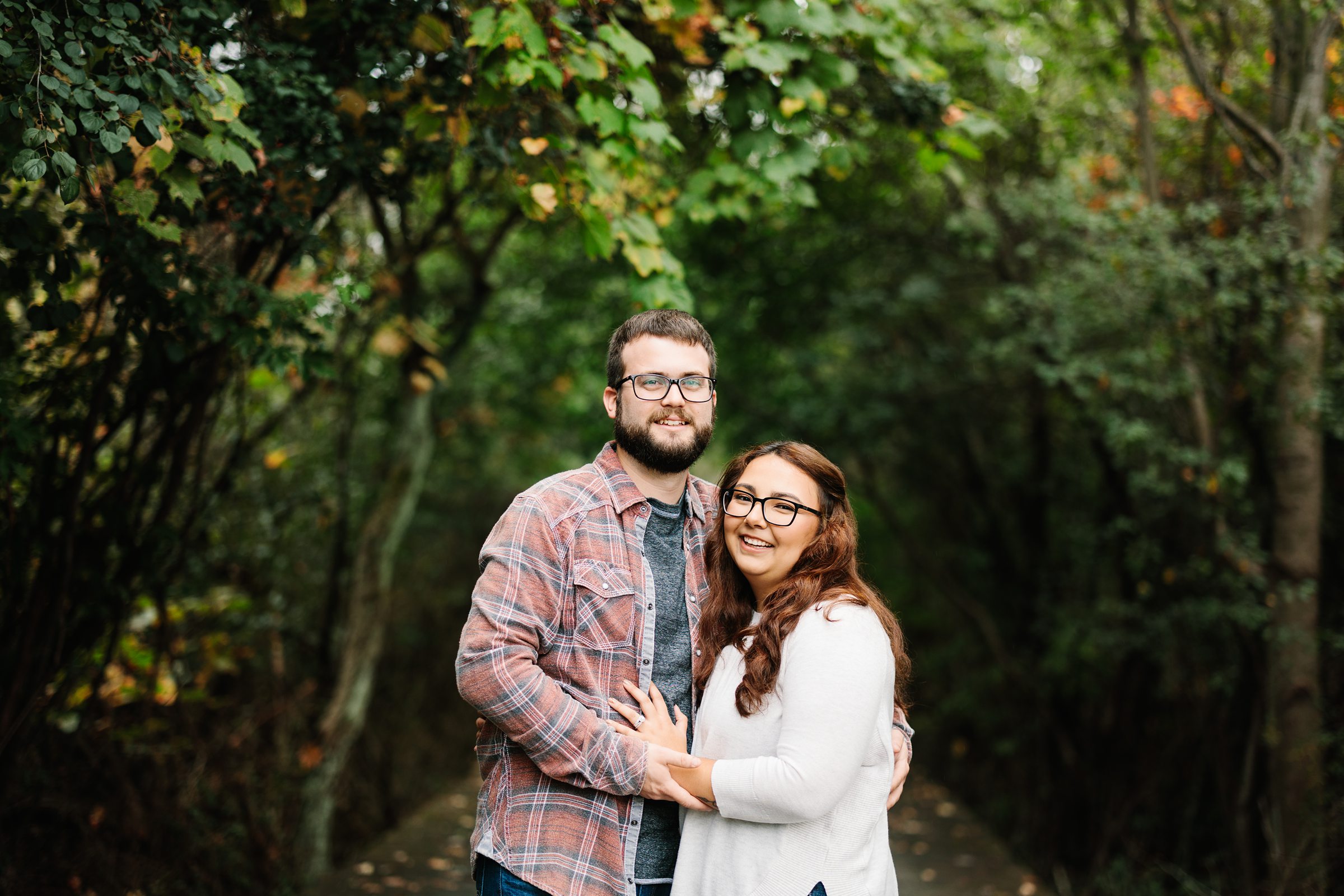 Engaged couple holds each other and smiles at the camera for a fall engagement session by Detroit Wedding Photographer Michele Maloney