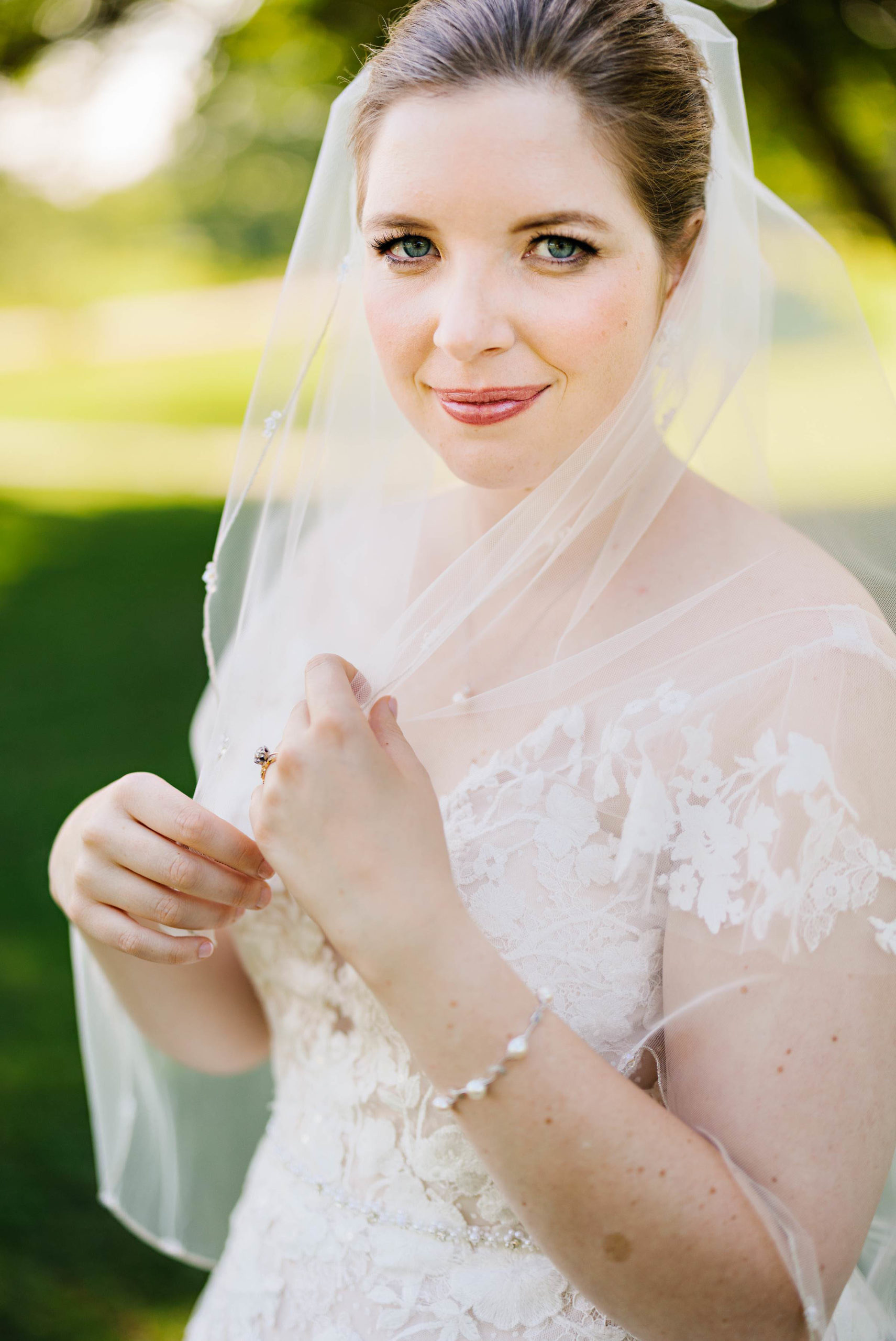Bride smiles for photo and plays with veil by Detroit Wedding Photographer Michele Maloney