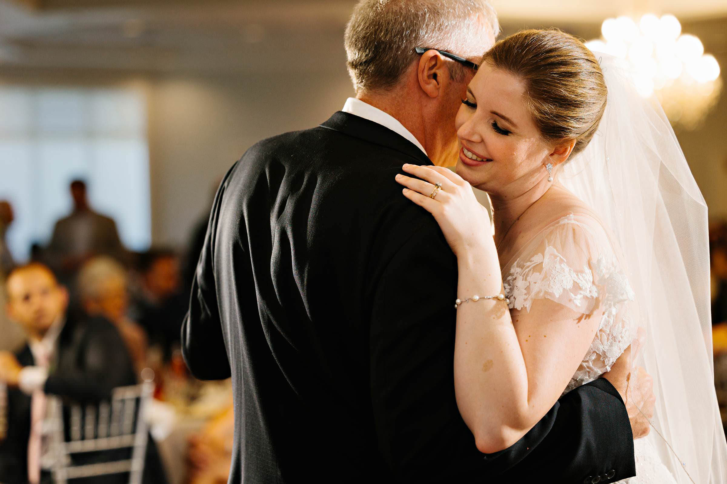 Bride smiles during father daughter dance by Detroit Wedding Photographer Michele Maloney