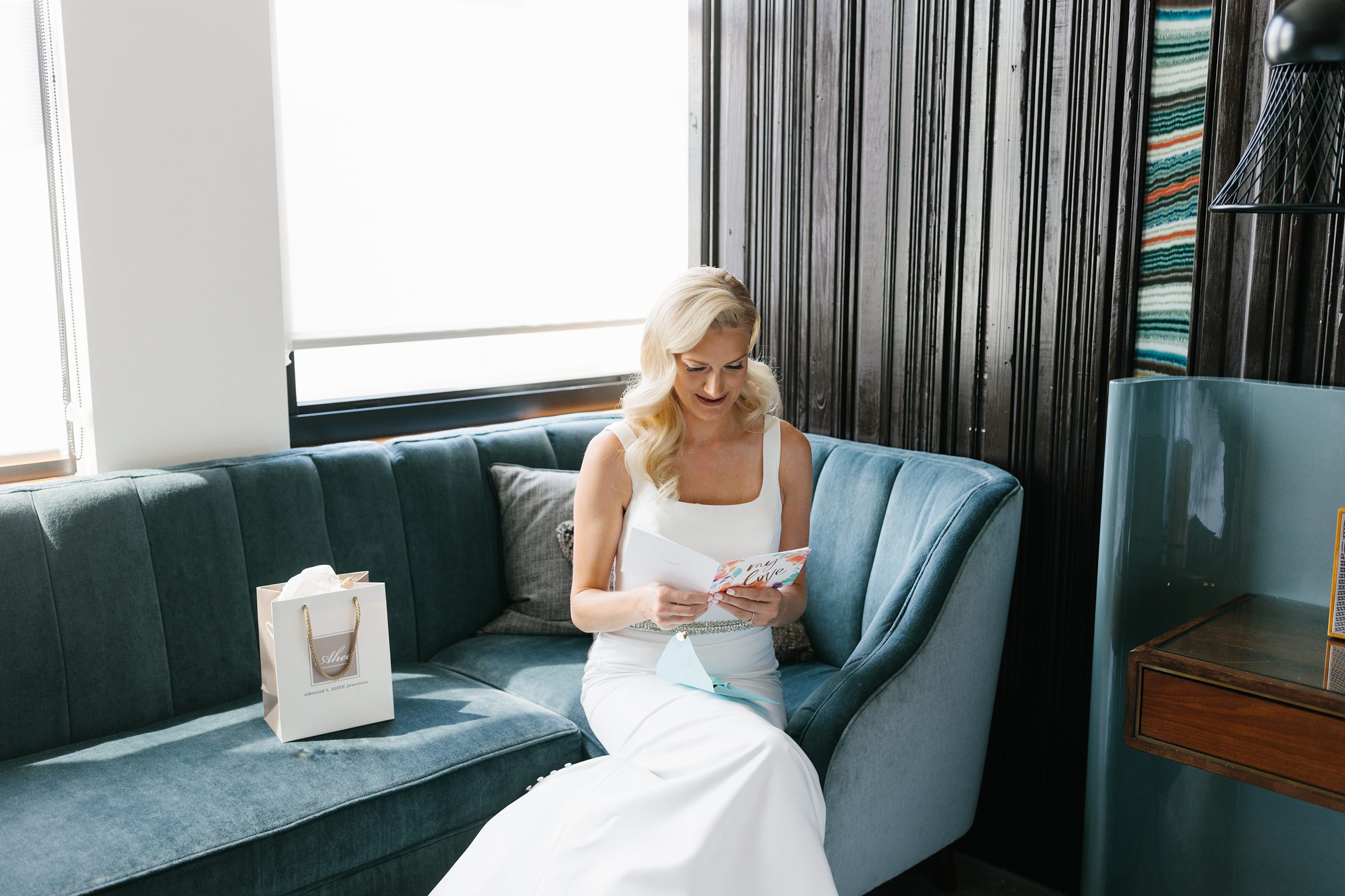 Bride sitting and reading a card and opening a gift before the ceremony by Detroit Wedding Photographer Michele Maloney