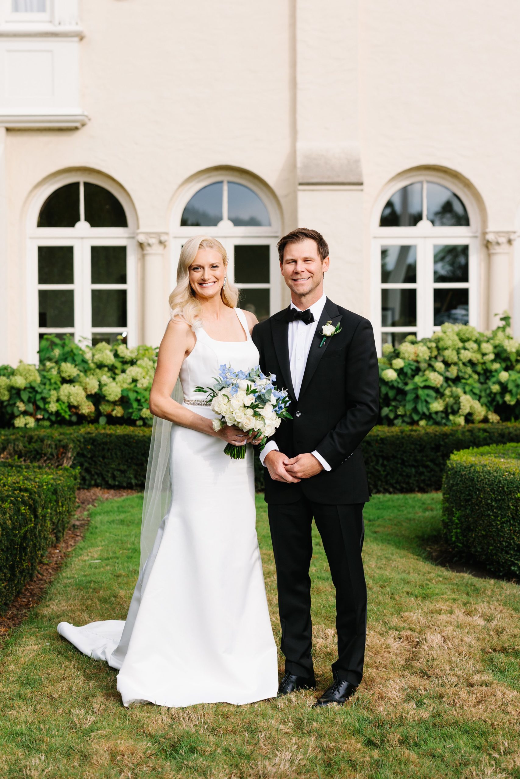 The bride and groom smile for portraits outside of the Grosse Pointe Yacht Club by Detroit Wedding Photographer Michele Maloney