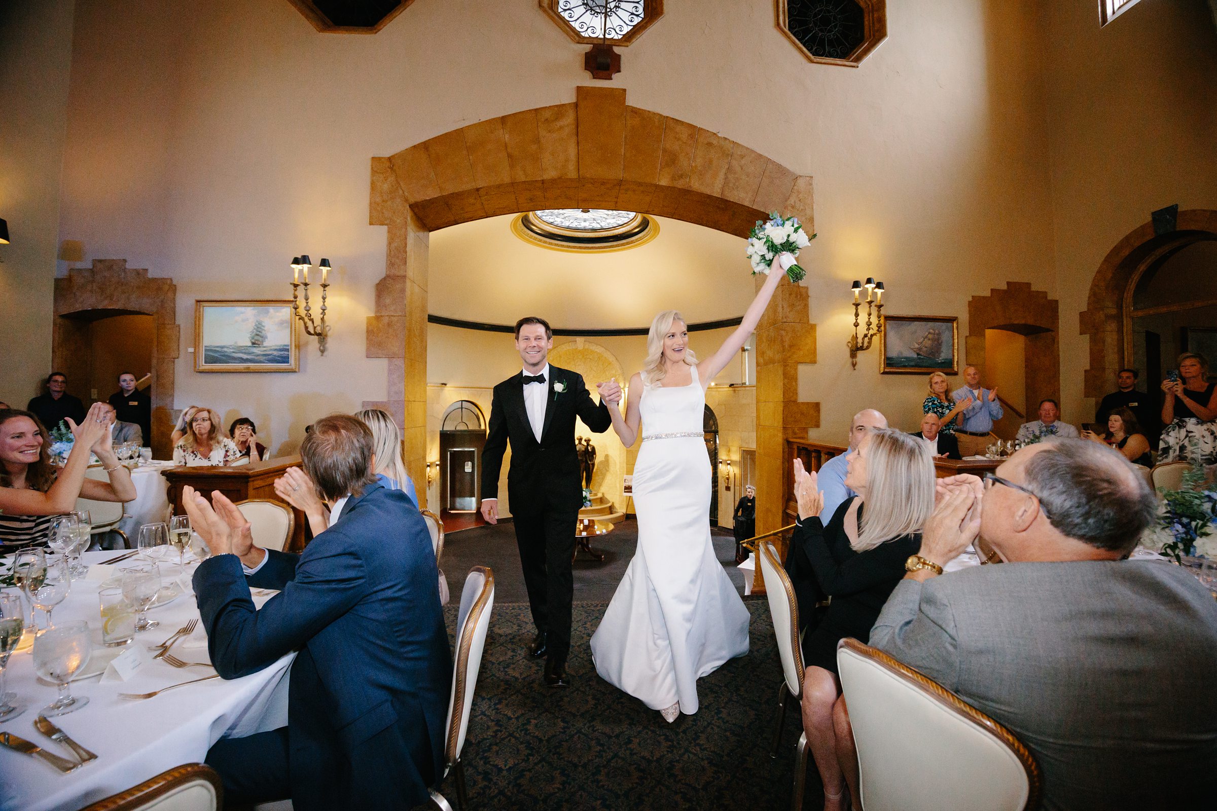 Bride and groom walk into the reception for introductions at the Grosse Pointe Yacht Club by Detroit Wedding Photographer Michele Maloney