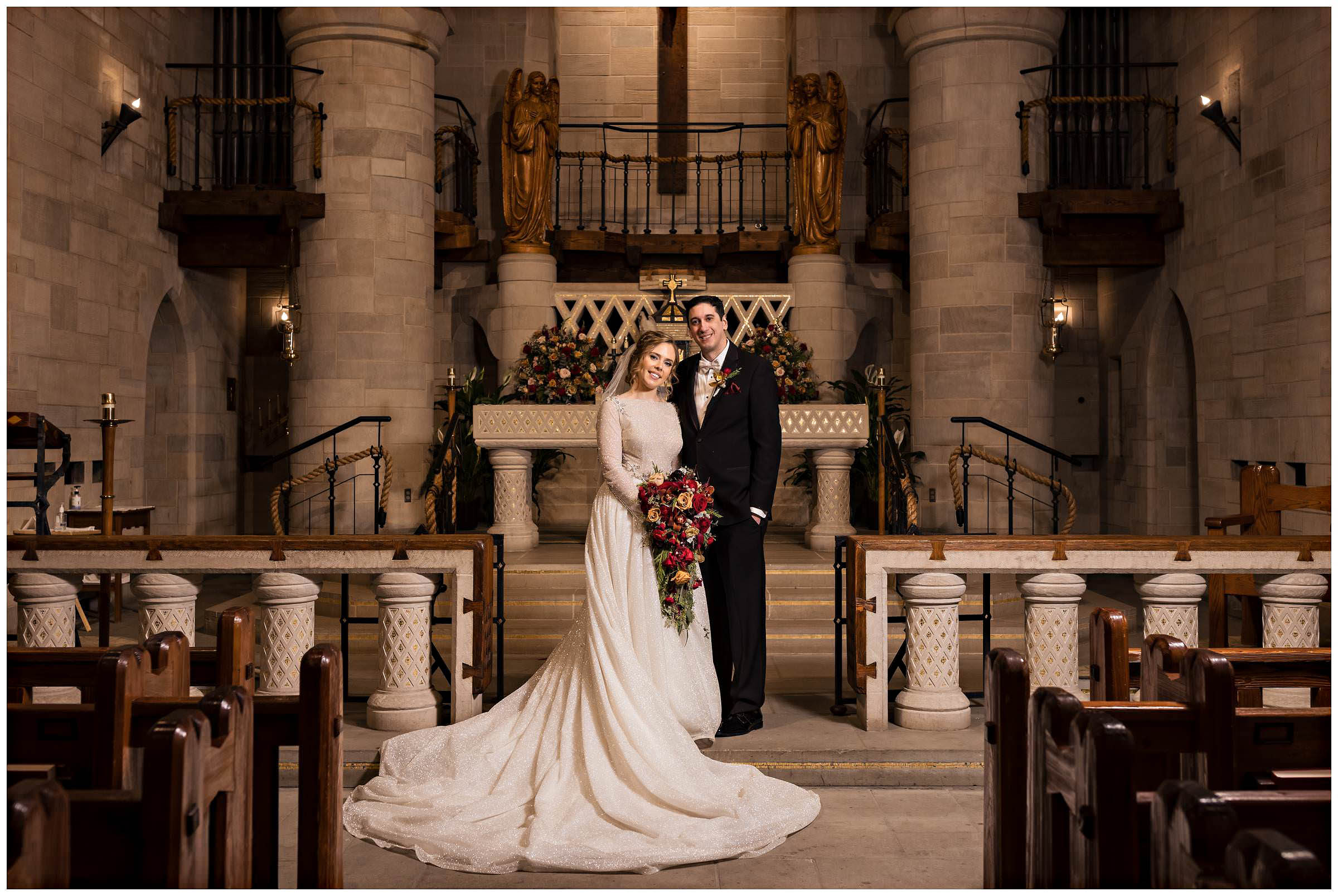 Bride and groom smile at the camera in an empty church by Detroit Wedding Photographer Michele Maloney