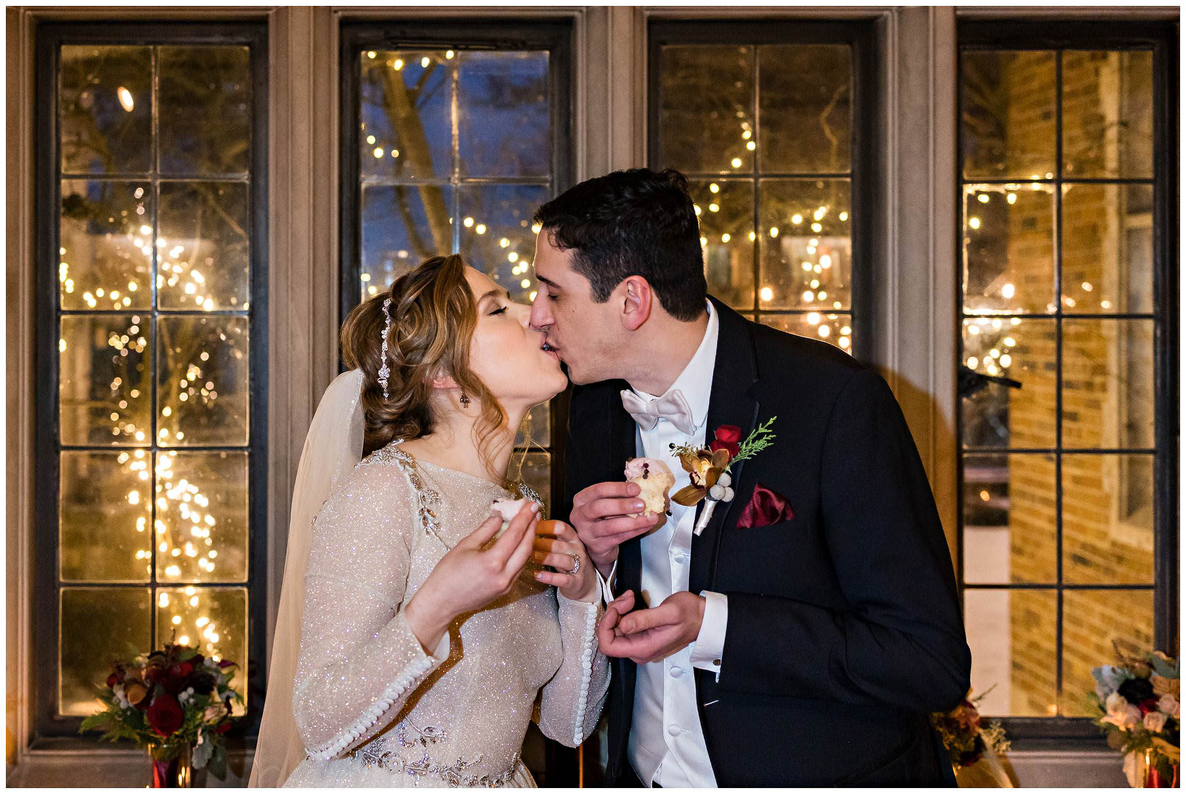 Bride and groom kiss with cupcakes in their hands by Detroit Wedding Photographer Michele Maloney