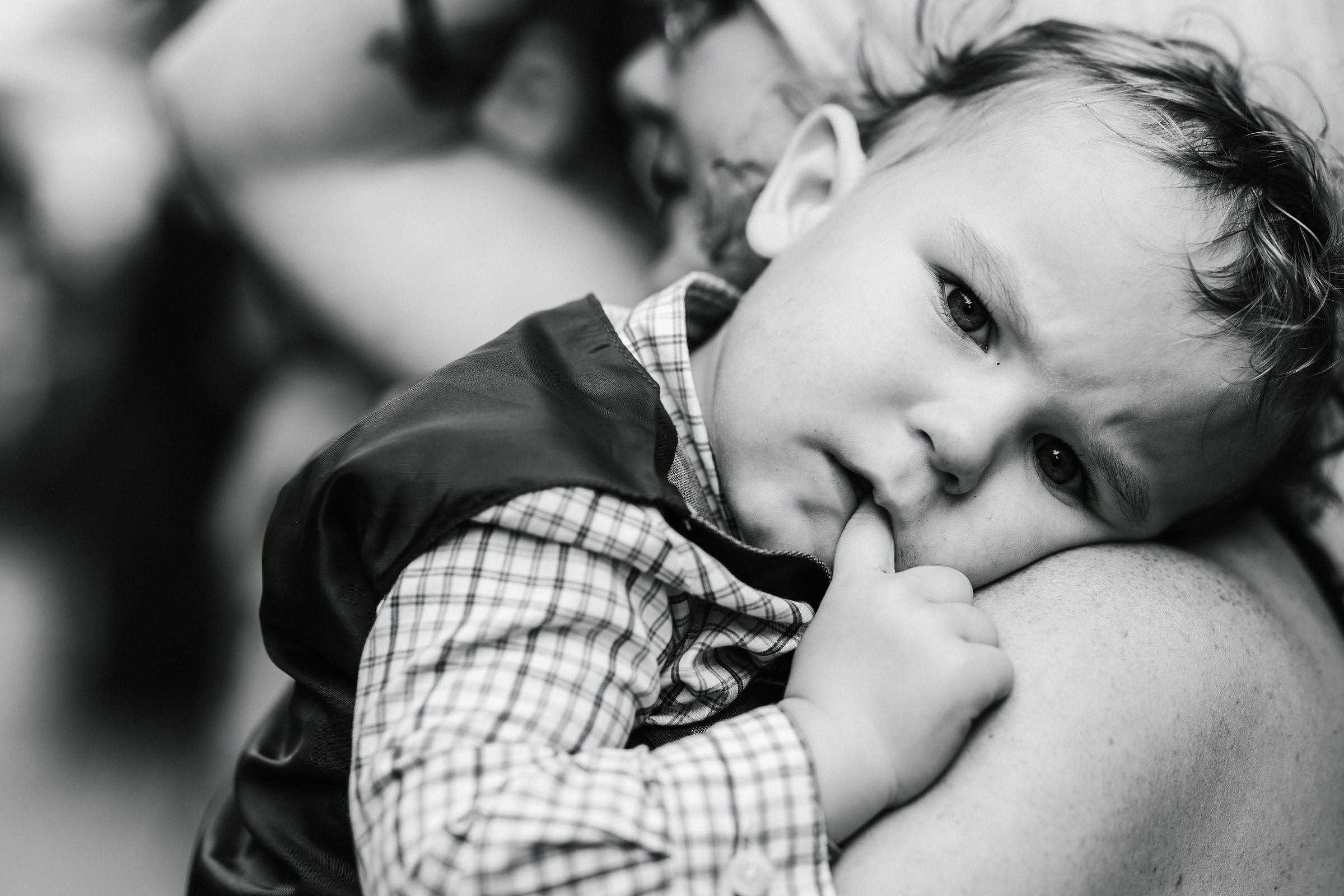 Black and white photo of child laying on shoulder and looking at camera after the wedding ceremony by Detroit Wedding Photographer Michele Maloney 