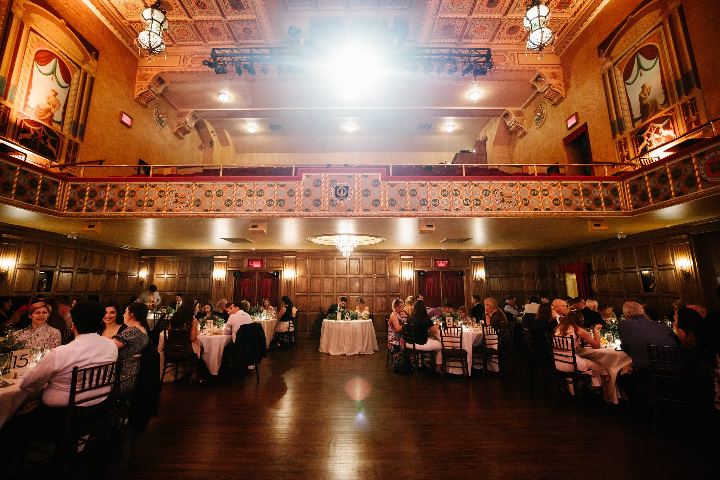 Faraway shot of the guests and bridal party sitting at their tables during the reception at the Gem Theater by Detroit Wedding Photographer Michele Maloney