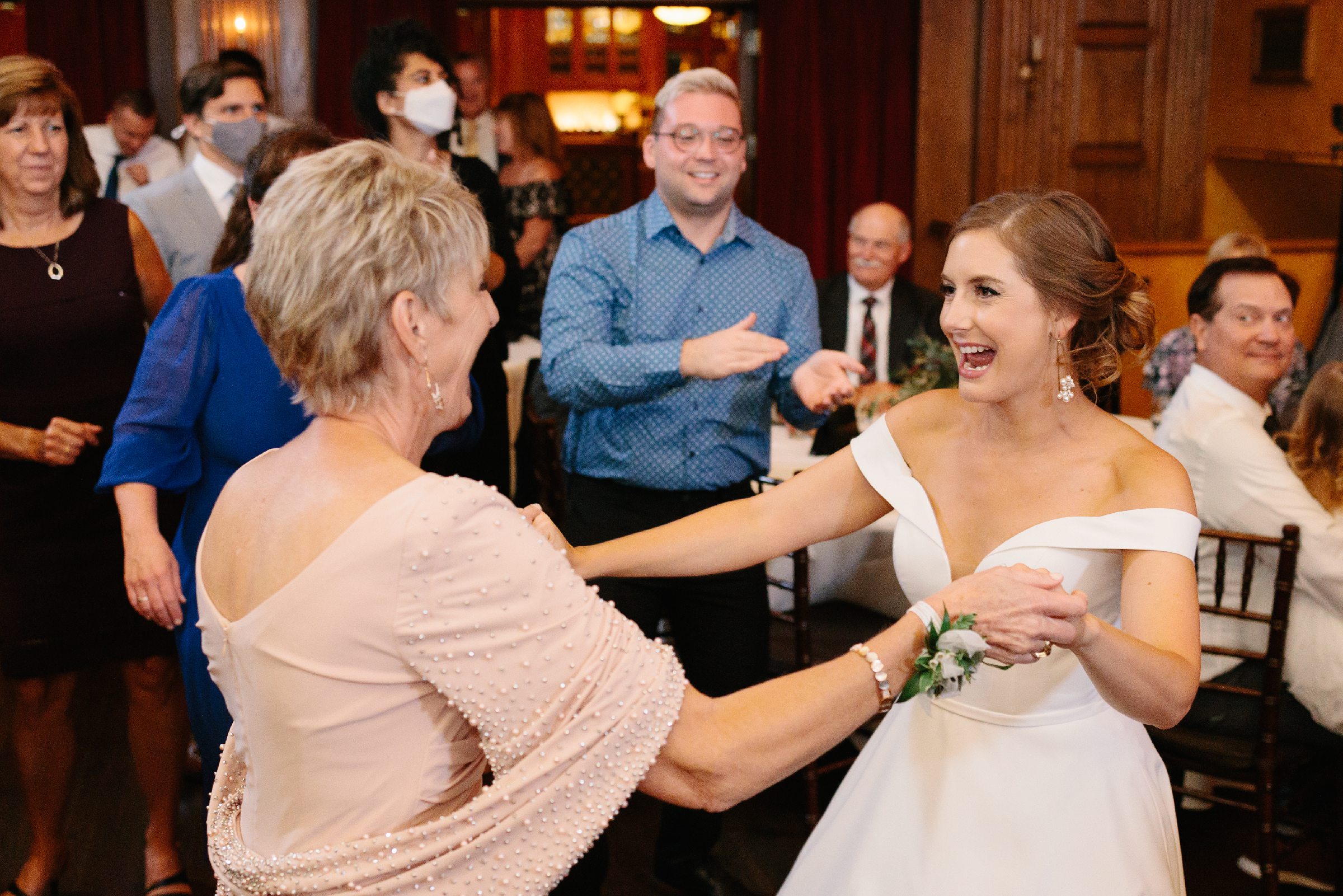 Bride and mother of the bride dance and laugh together at the reception by Detroit Wedding Photographer Michele Maloney
