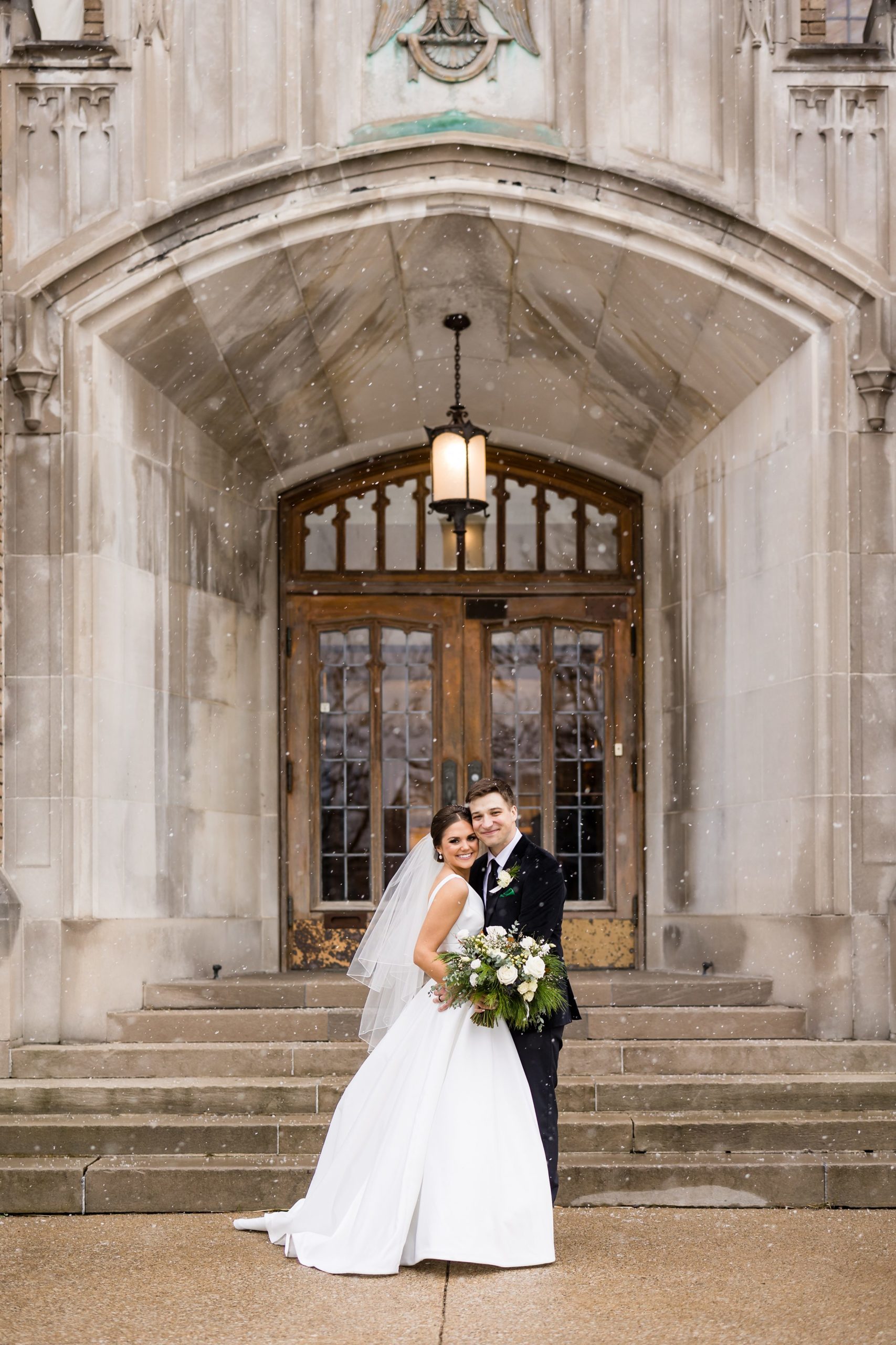 Bride and groom pose for a portrait outside while it snows by Detroit Wedding Photographer Michele Maloney 