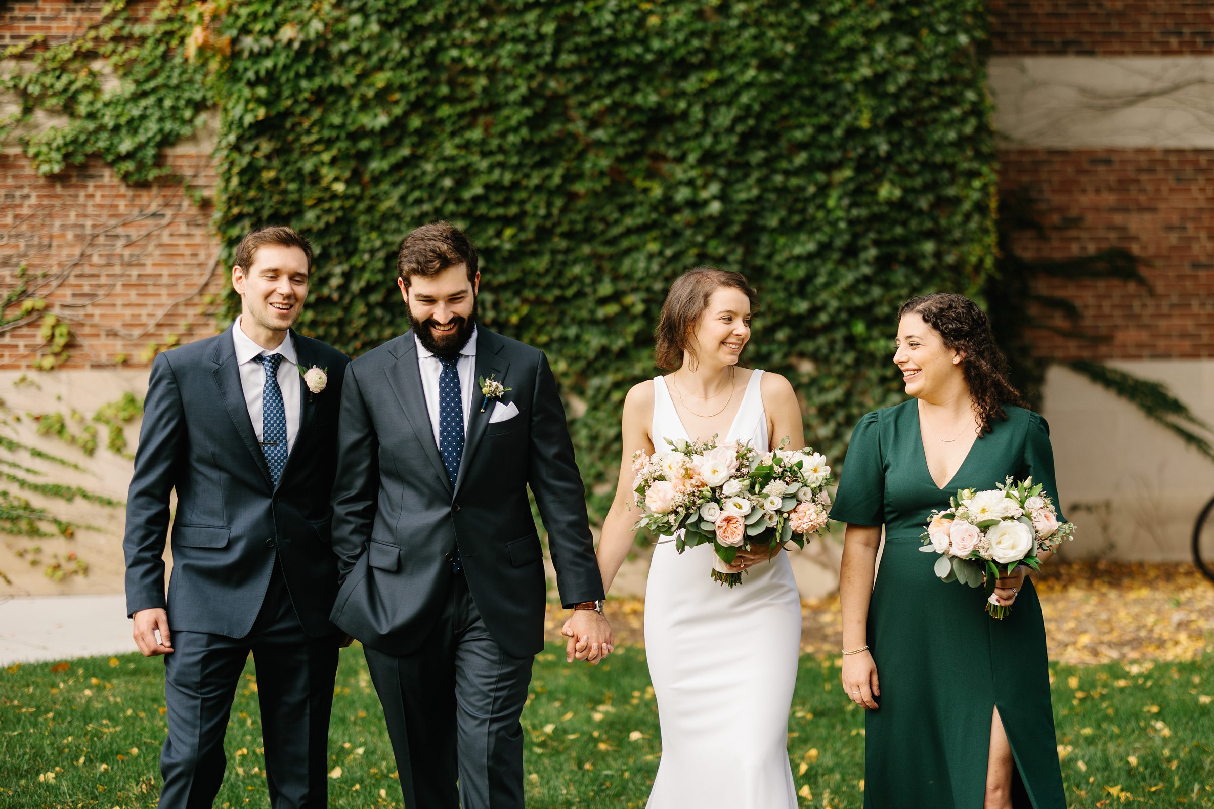 Bride and groom hold hands with loved ones on either side of them, all are laughing and taking a stroll by Detroit Wedding Photographer Michele Maloney