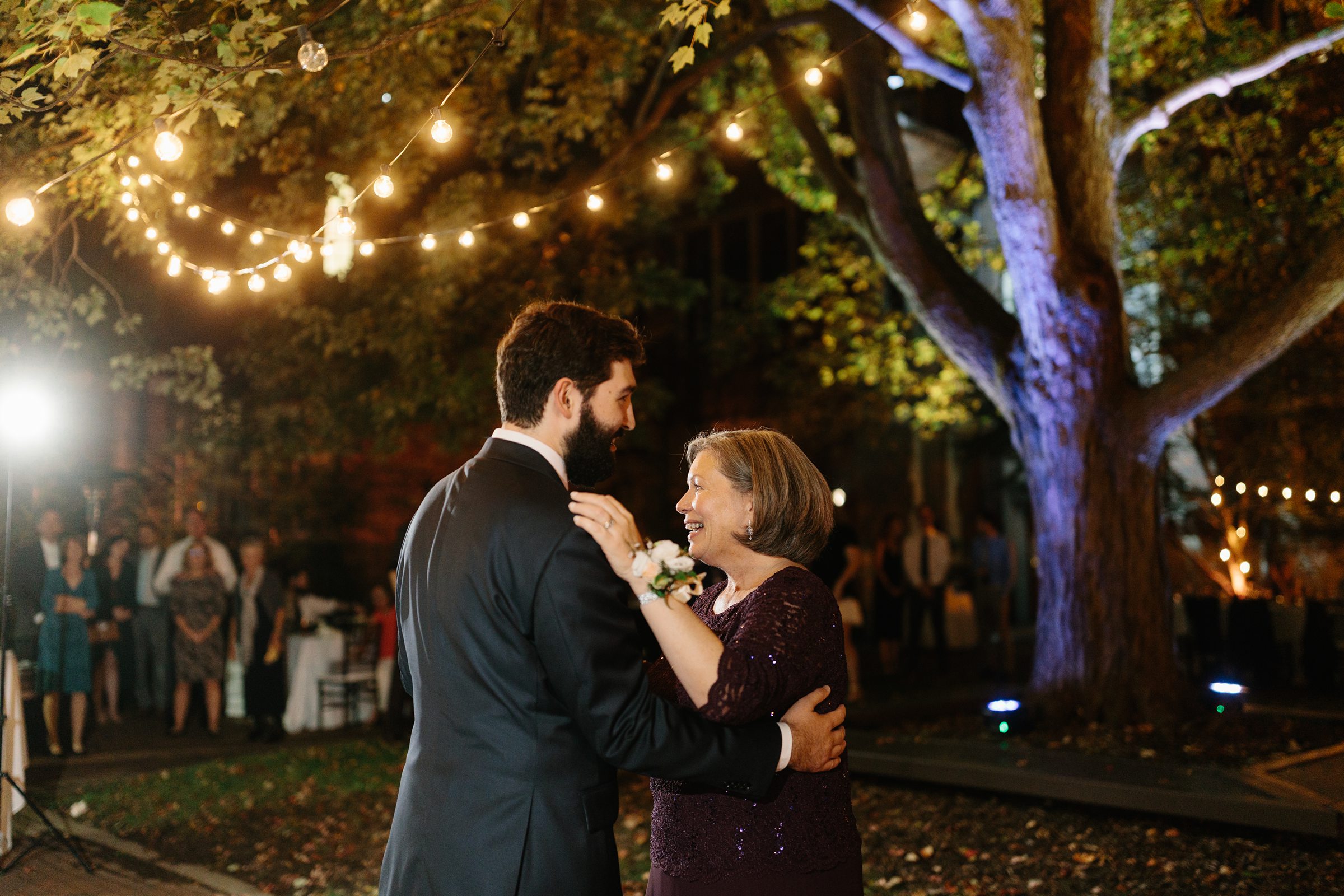 Groom and groom's mother slow dance under outdoor lights by Detroit Wedding Photographer Michele Maloney 