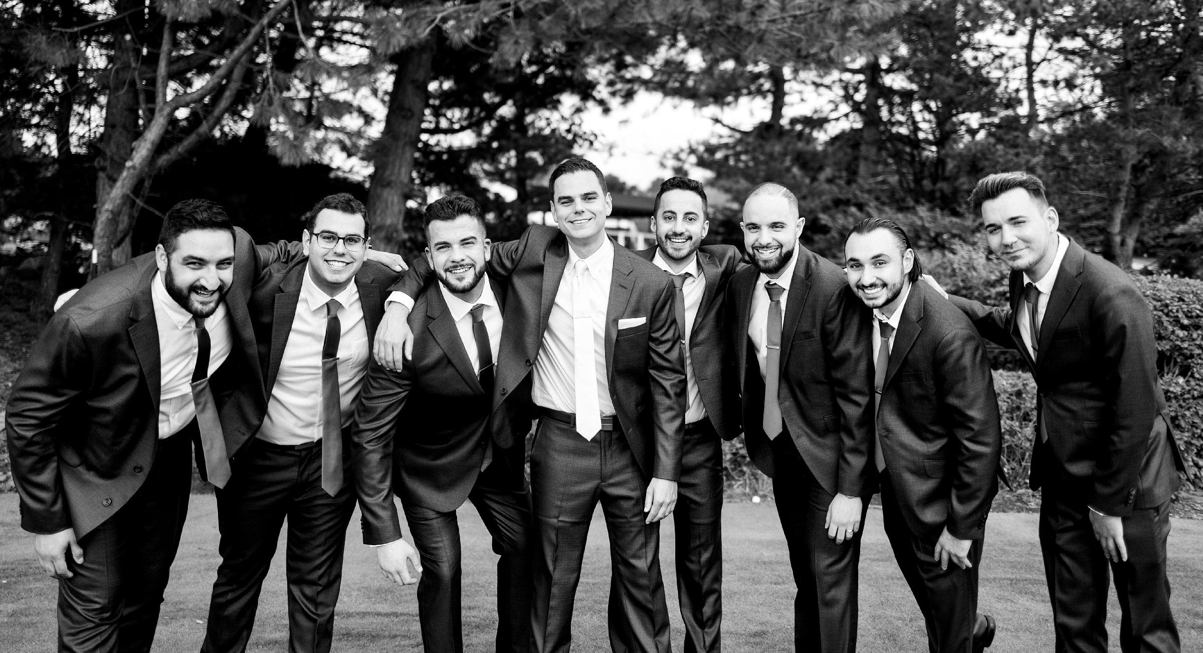 Black and white photo of the groom and groomsmen smiling with their arms around each other by Detroit Wedding Photographer Michele Maloney