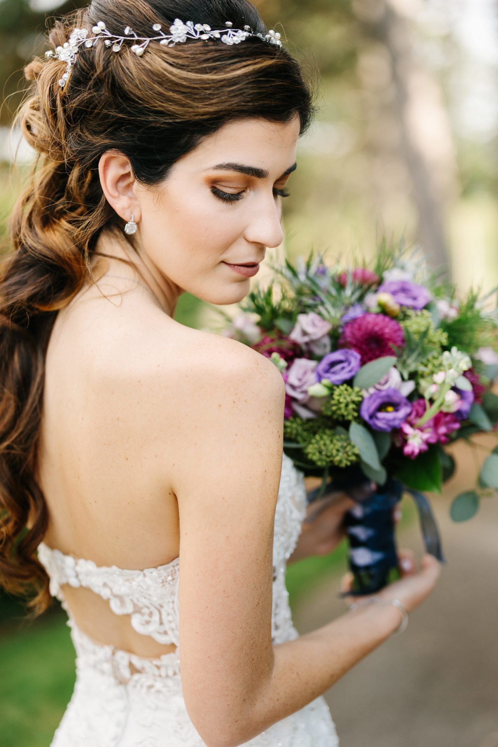 Bride looks down over her shoulder while holding her bouquet by Detroit Wedding Photographer Michele Maloney