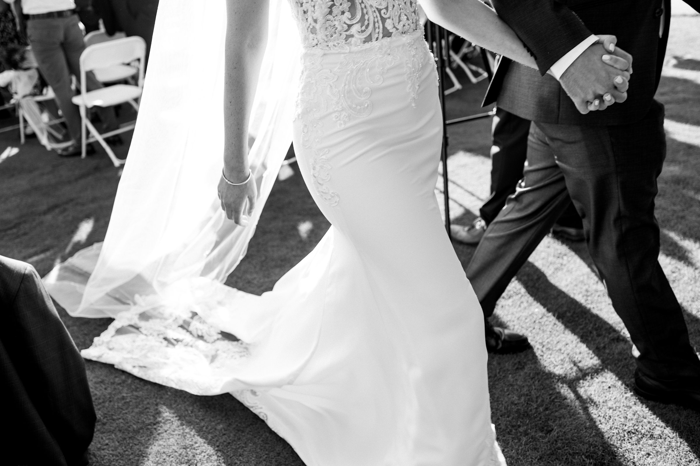 Black and white photo of bride and groom holding hands as they exit the ceremony by Detroit Wedding Photographer Michele Maloney