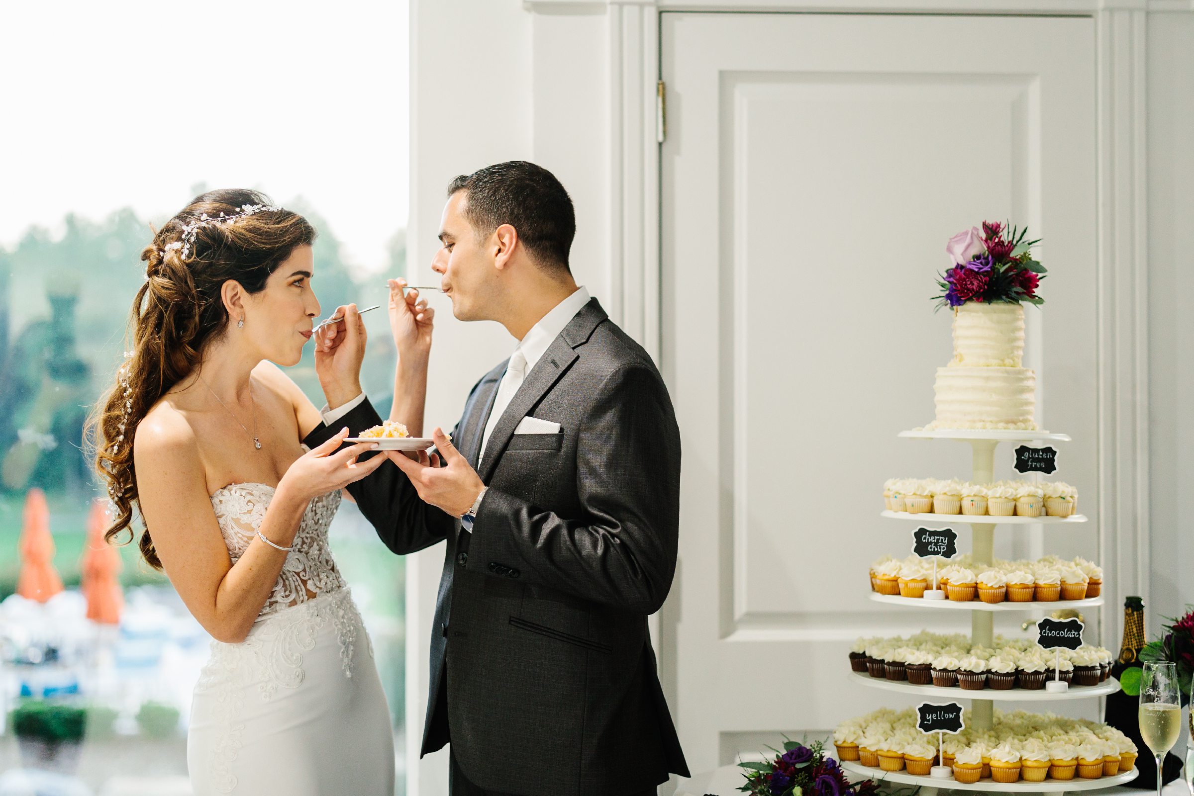 Bride and groom feed each other a piece of wedding cake at the same time by Detroit Wedding Photographer Michele Maloney 