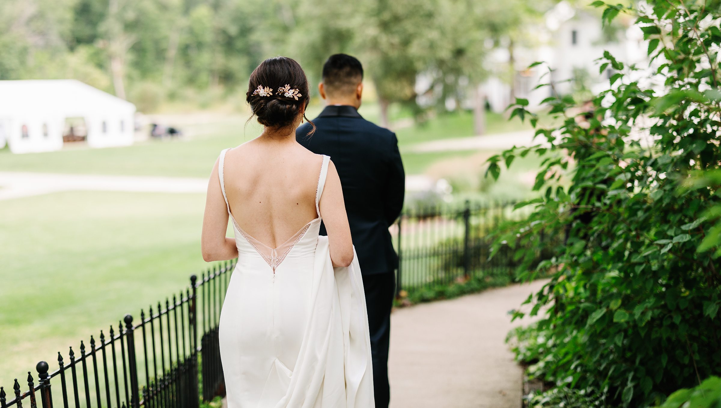 Shot from behind of bride walking up to groom during their first look for the Waldenwoods Summer wedding by Detroit Wedding Photographer Michele Maloney