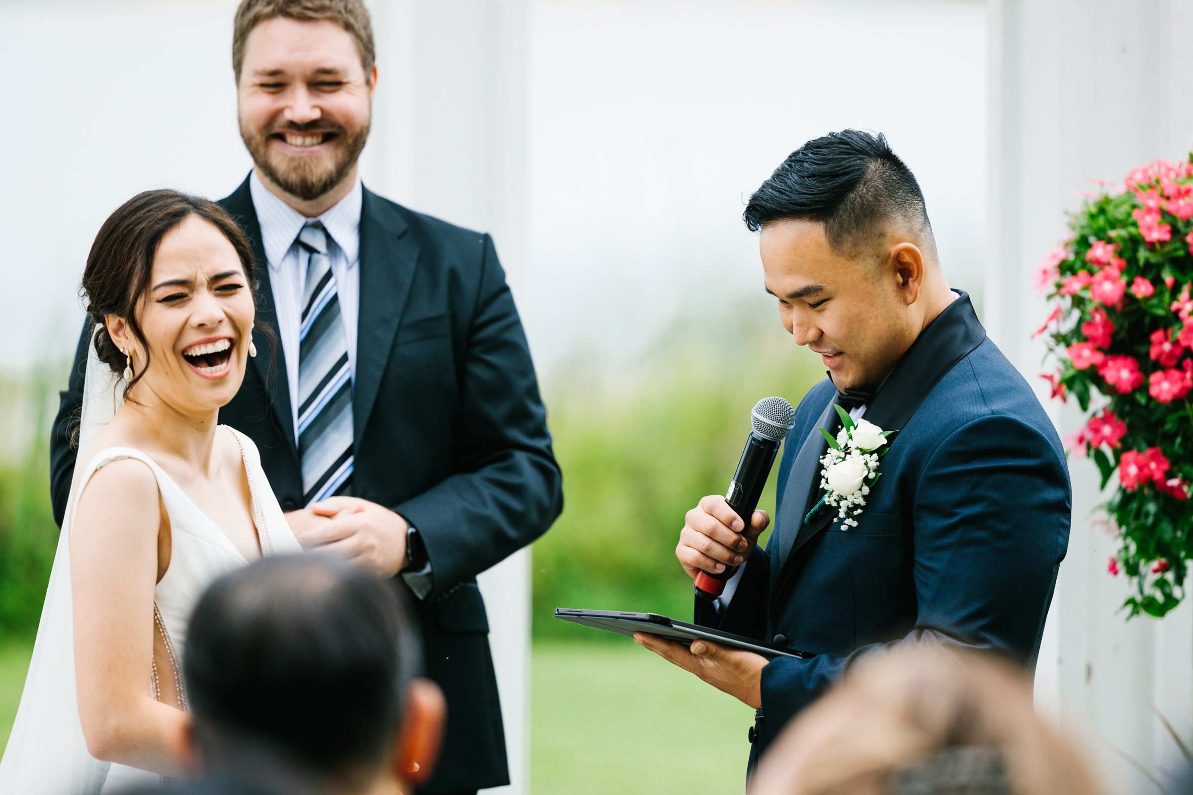 Bride laughs while groom reads his vows during their Waldenwoods summer wedding by Detroit Wedding Photographer Michele Maloney