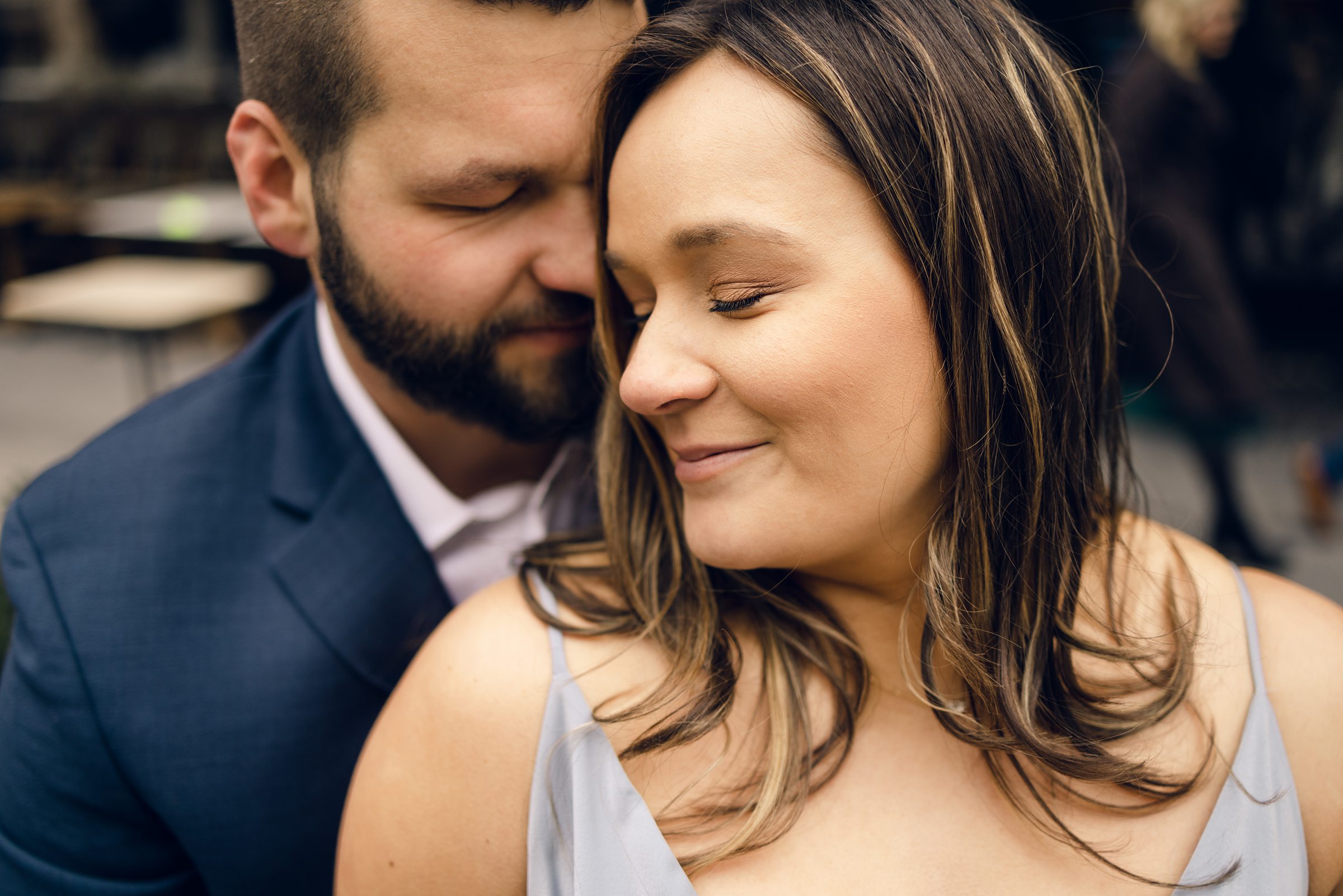 man and woman snuggling during their Detroit Engagement Session in front of Shinola Hotel