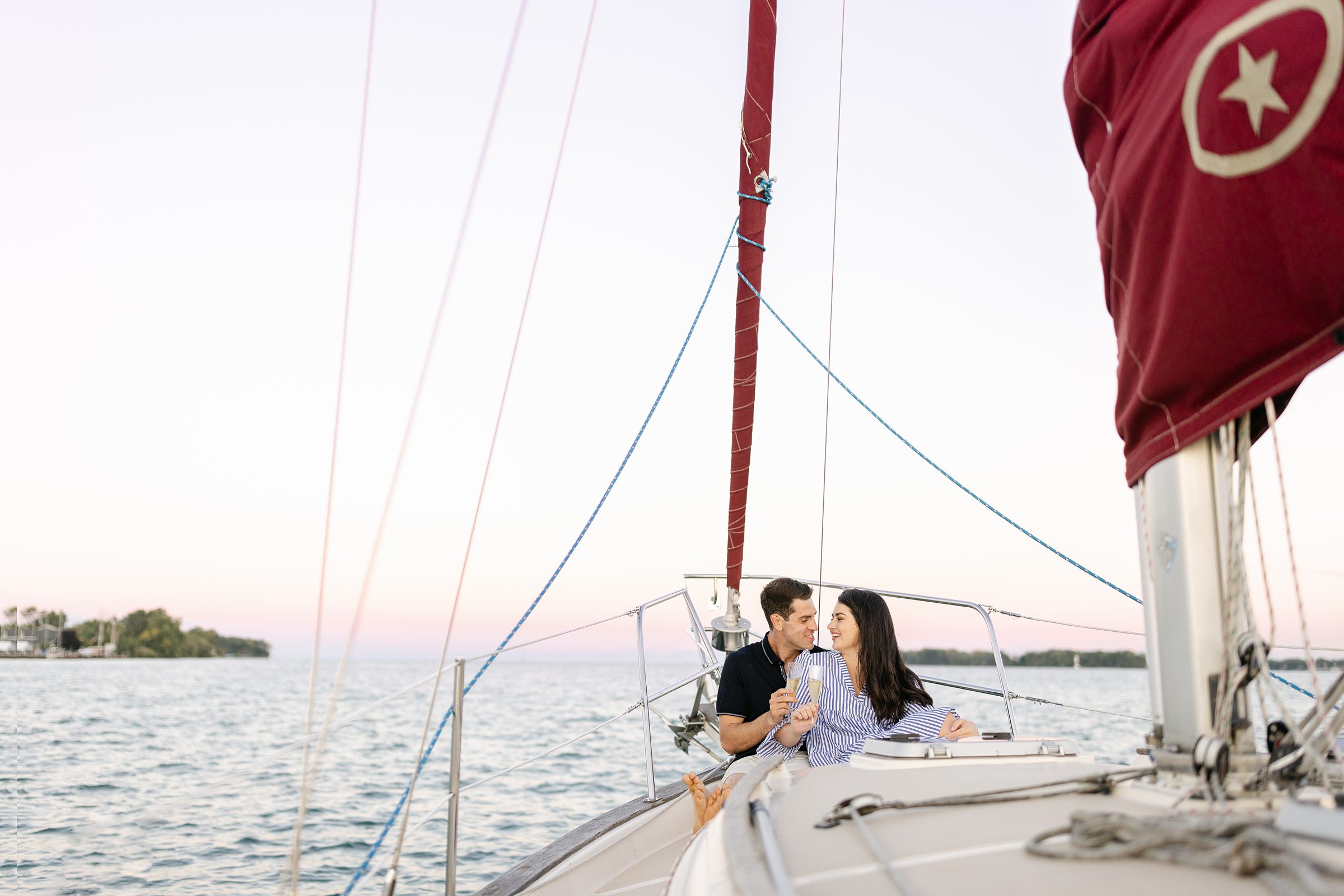 couple toasting with champagne at the end of their engagement session on a sailboat by Michele Maloney Photography