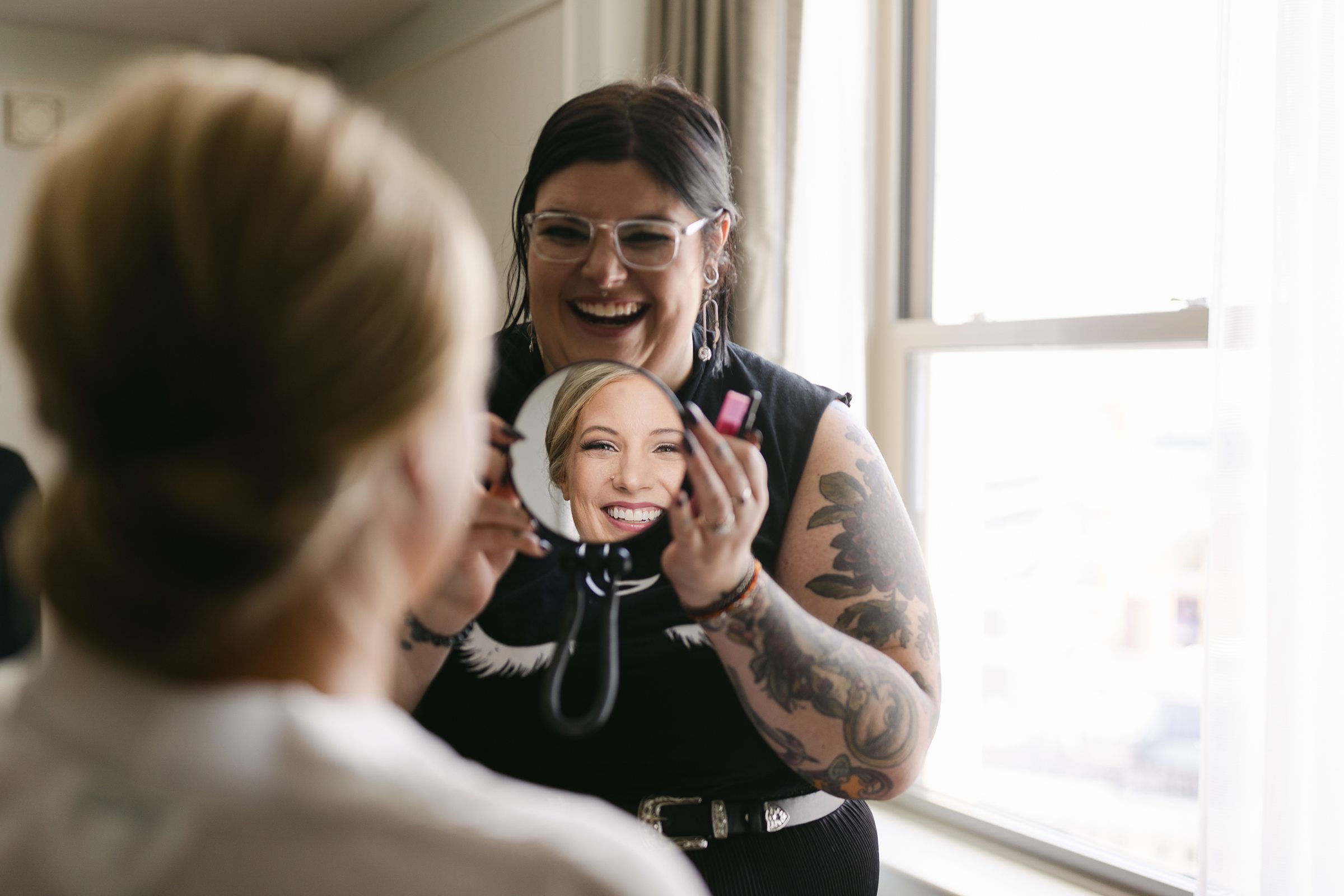 Hair and makeup artist showing bride the mirror