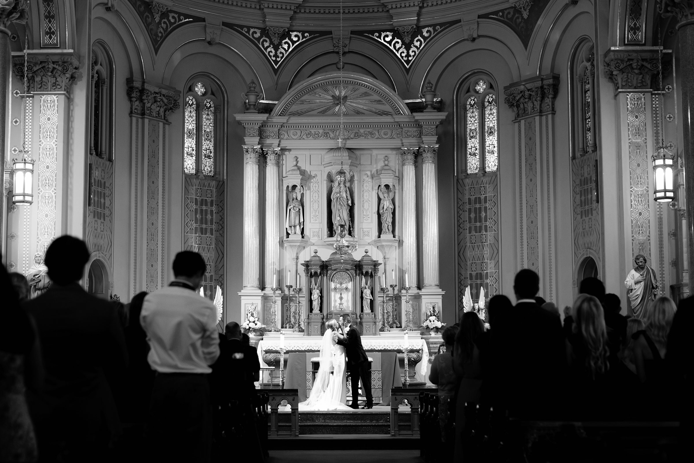 black and white photo of bride and groom kissing at the altar
