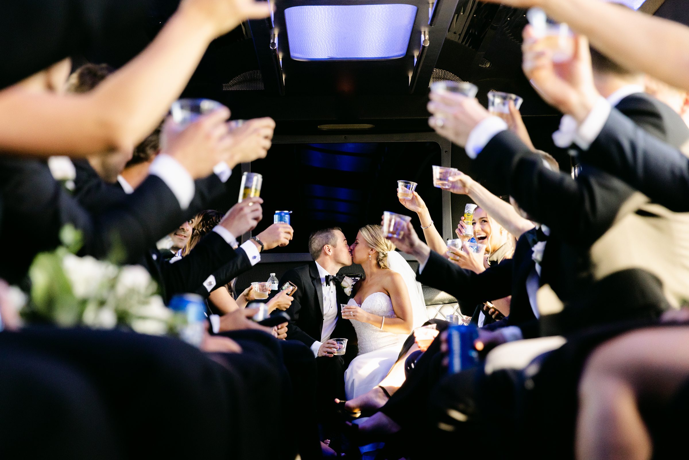 wedding party toasts to kissing couple on party bus