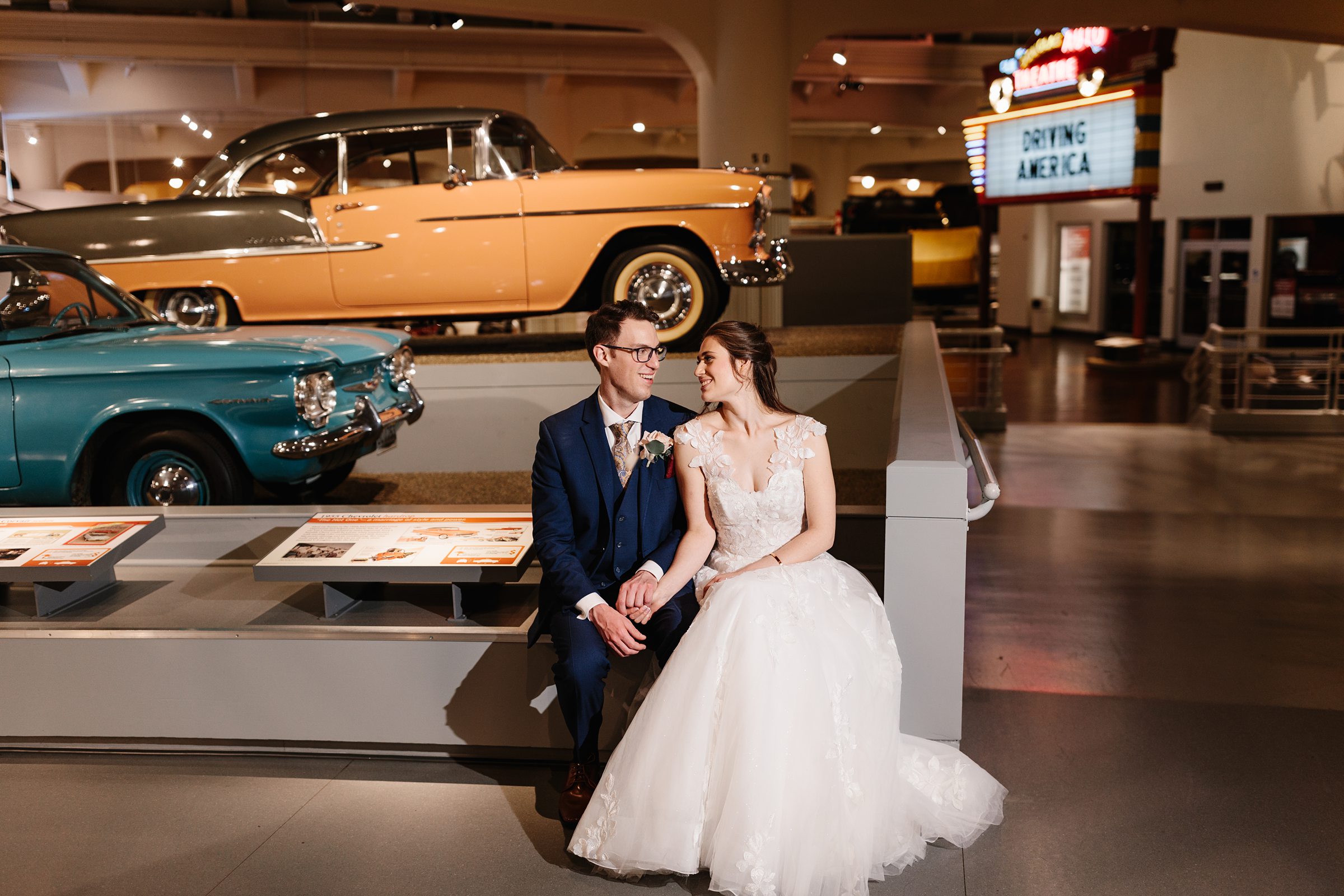 Couple sitting near the cars at the Henry Ford Museum by Michele Maloney Photography