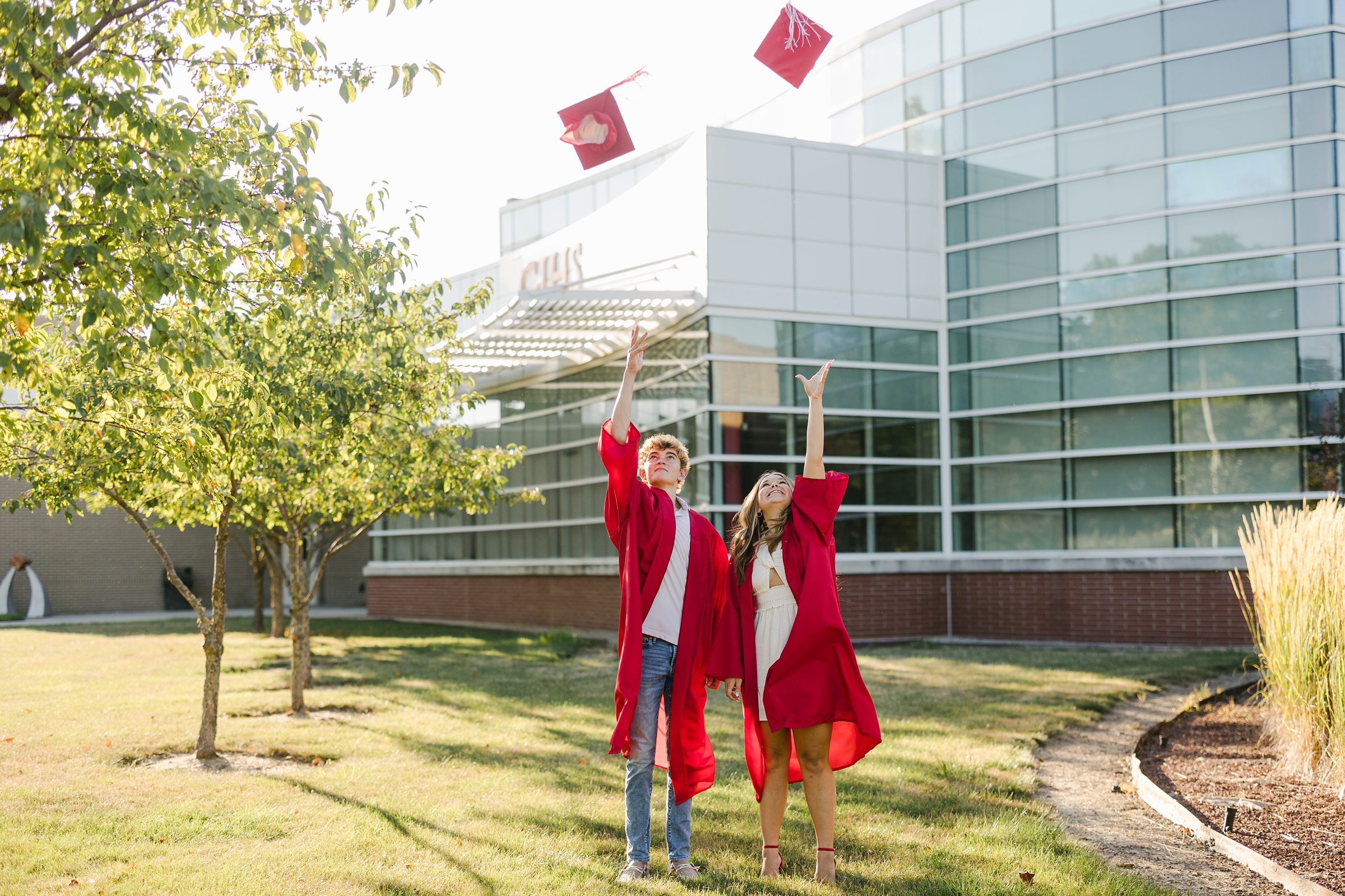 Two high school seniors throwing their caps at graduation in Grosse Ile Michigan by Michele Maloney Photography