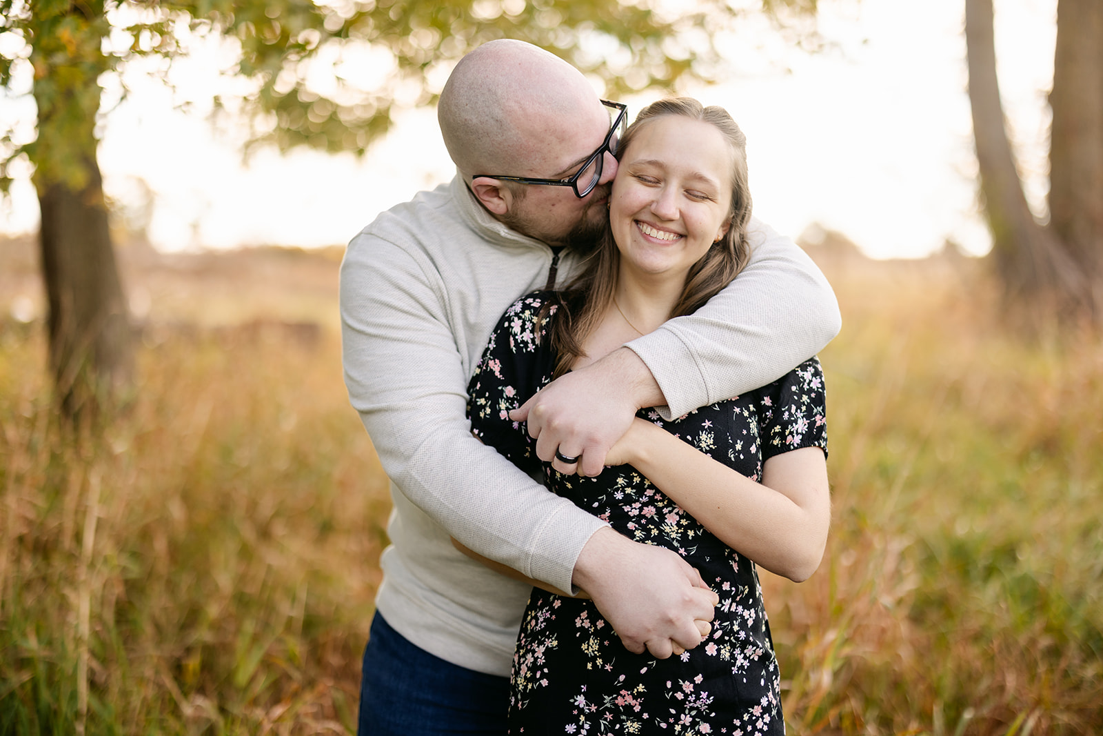 Brooke and Steven embracing beneath golden fall foliage at Lake Erie Metropark.