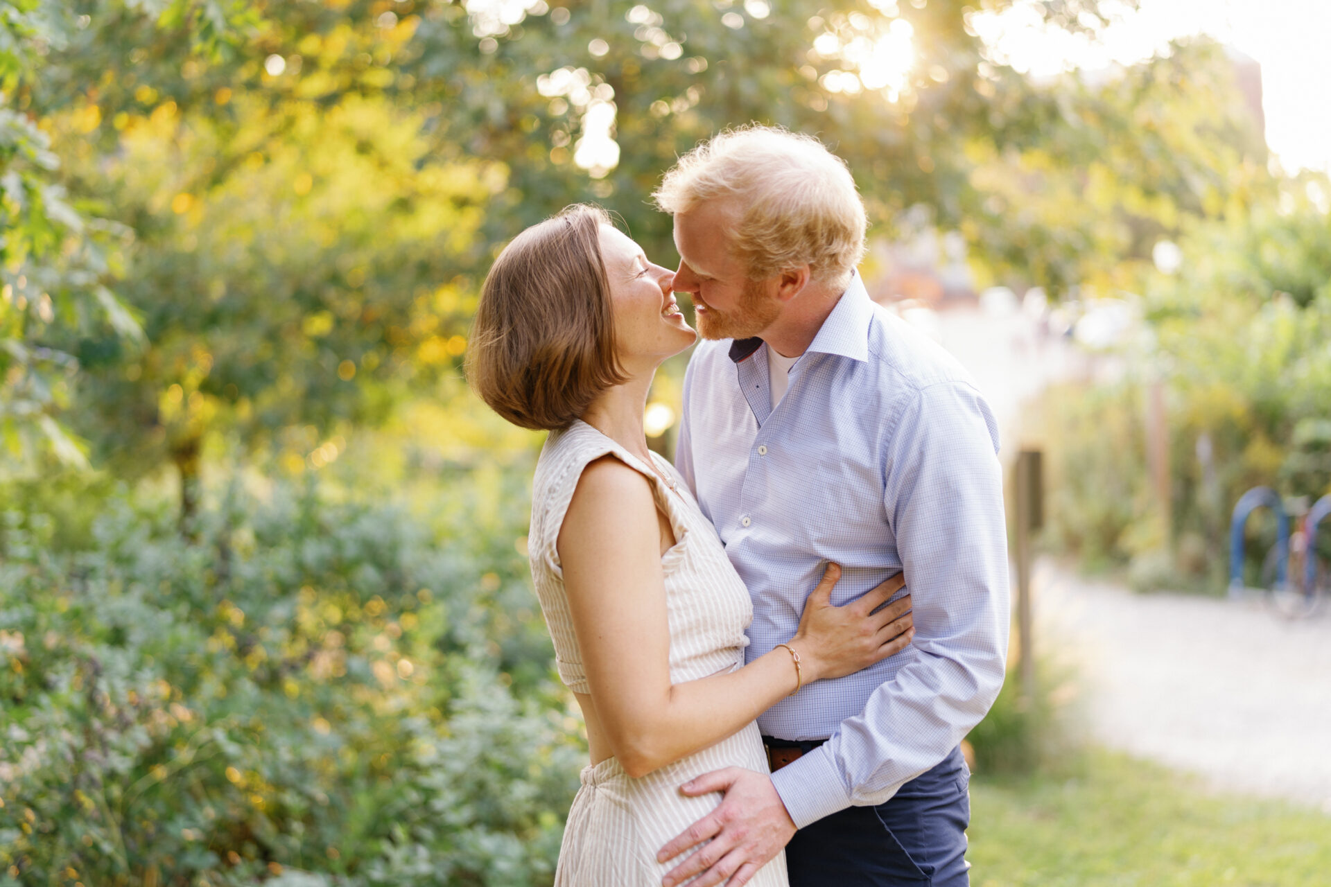 couple about to kiss with the light coming through the trees during their whimsical ann arbor engagement session