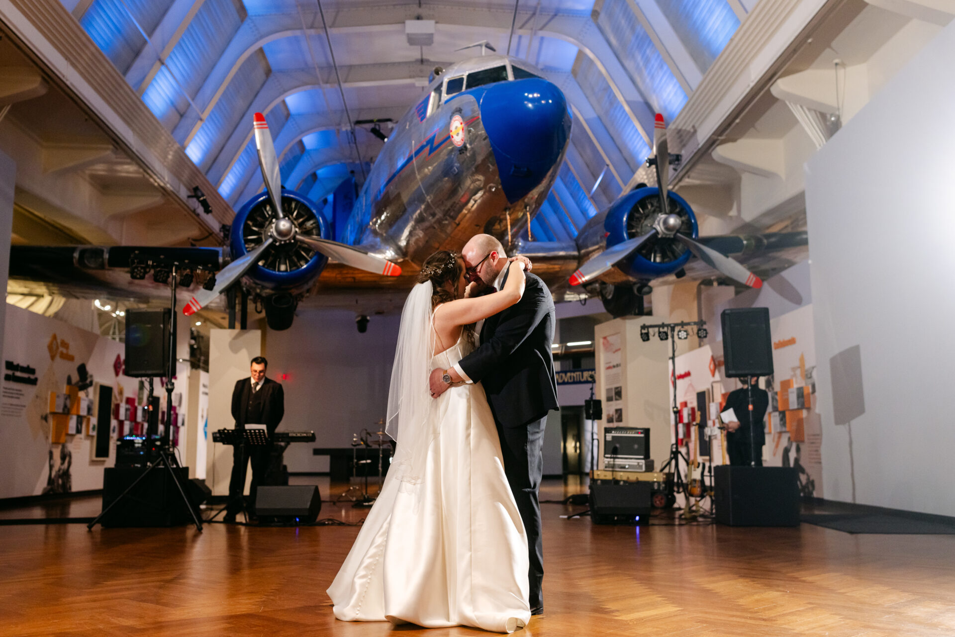 Melissa and Steven sharing an intimate moment beneath the vintage airplanes at the Henry Ford Museum.