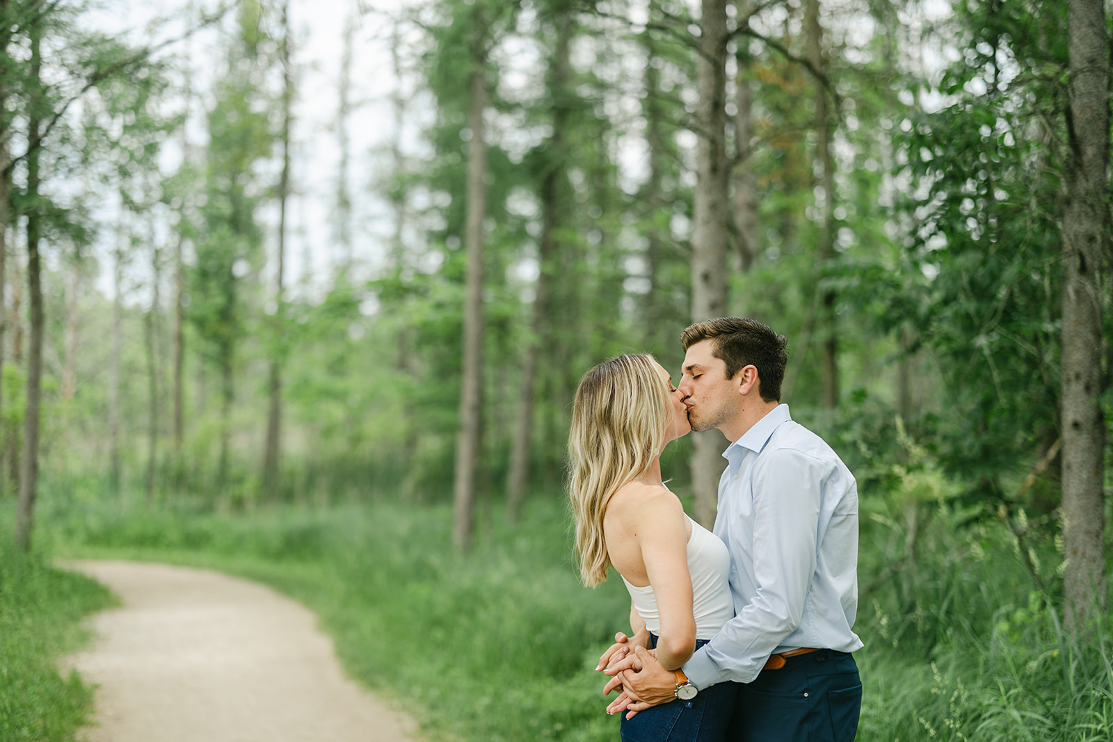 couple kissing on a trail during their effortless engagement session at Kensignton Metropark by Michele Maloney Photography