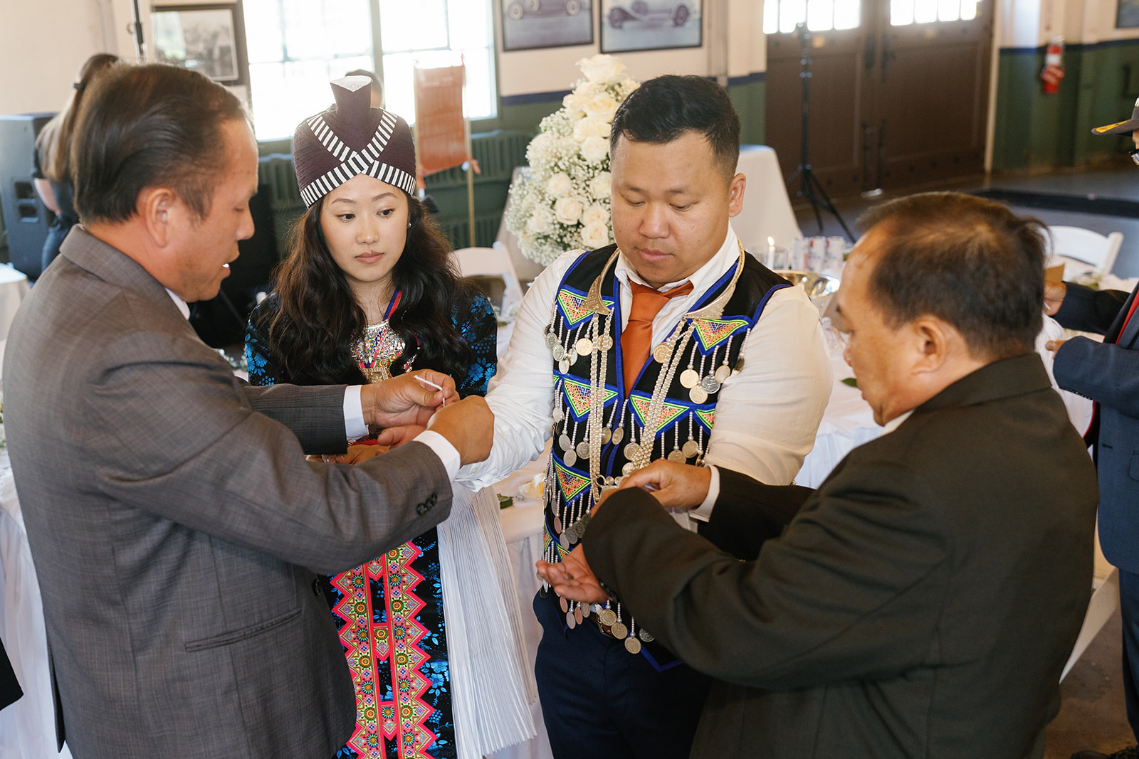 Couple surrounded by family during the khi tes ceremony at The Packard Proving Grounds.