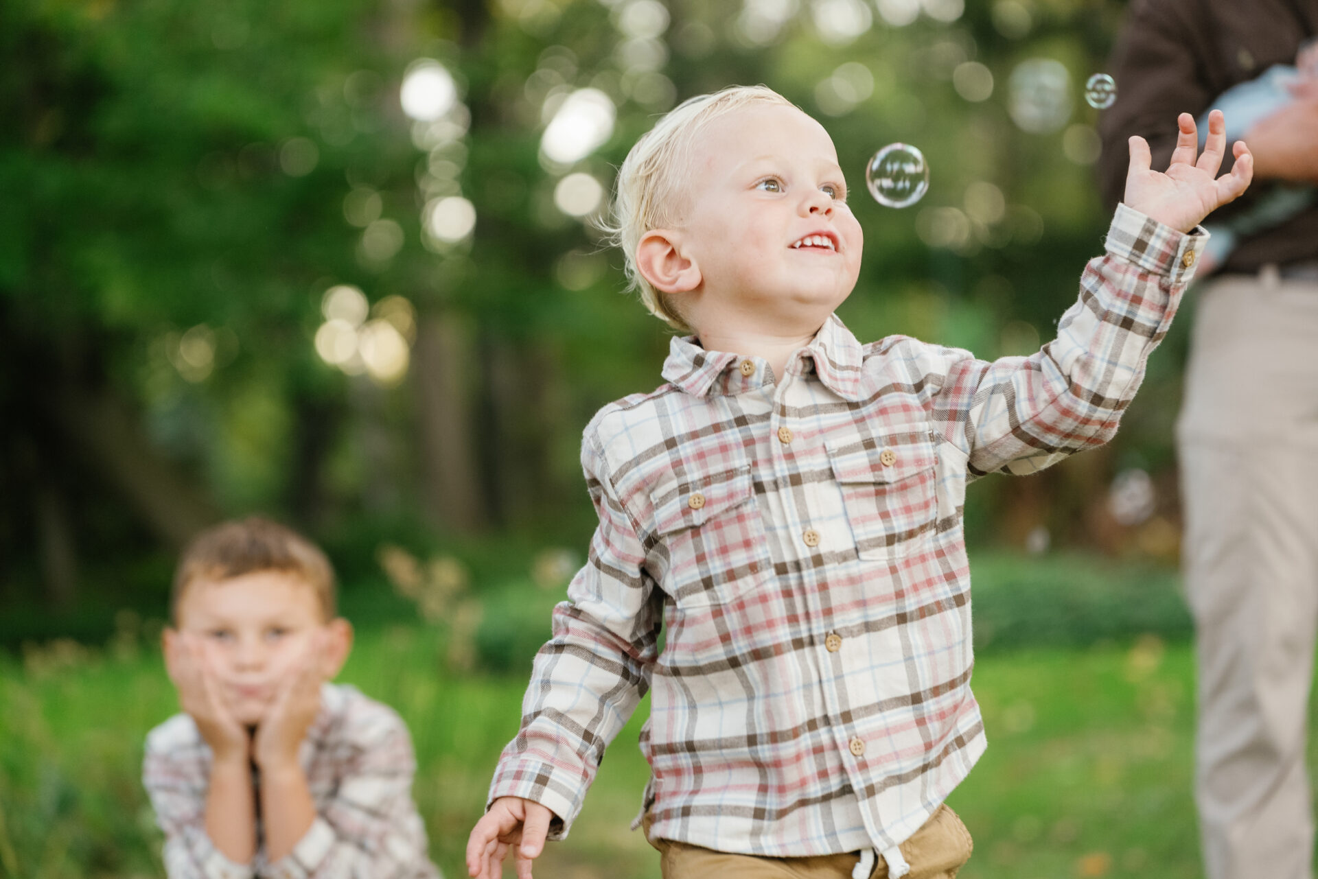 Joyful candid of the kids chasing bubbles through the garden | Grosse Ile Family Photos.
